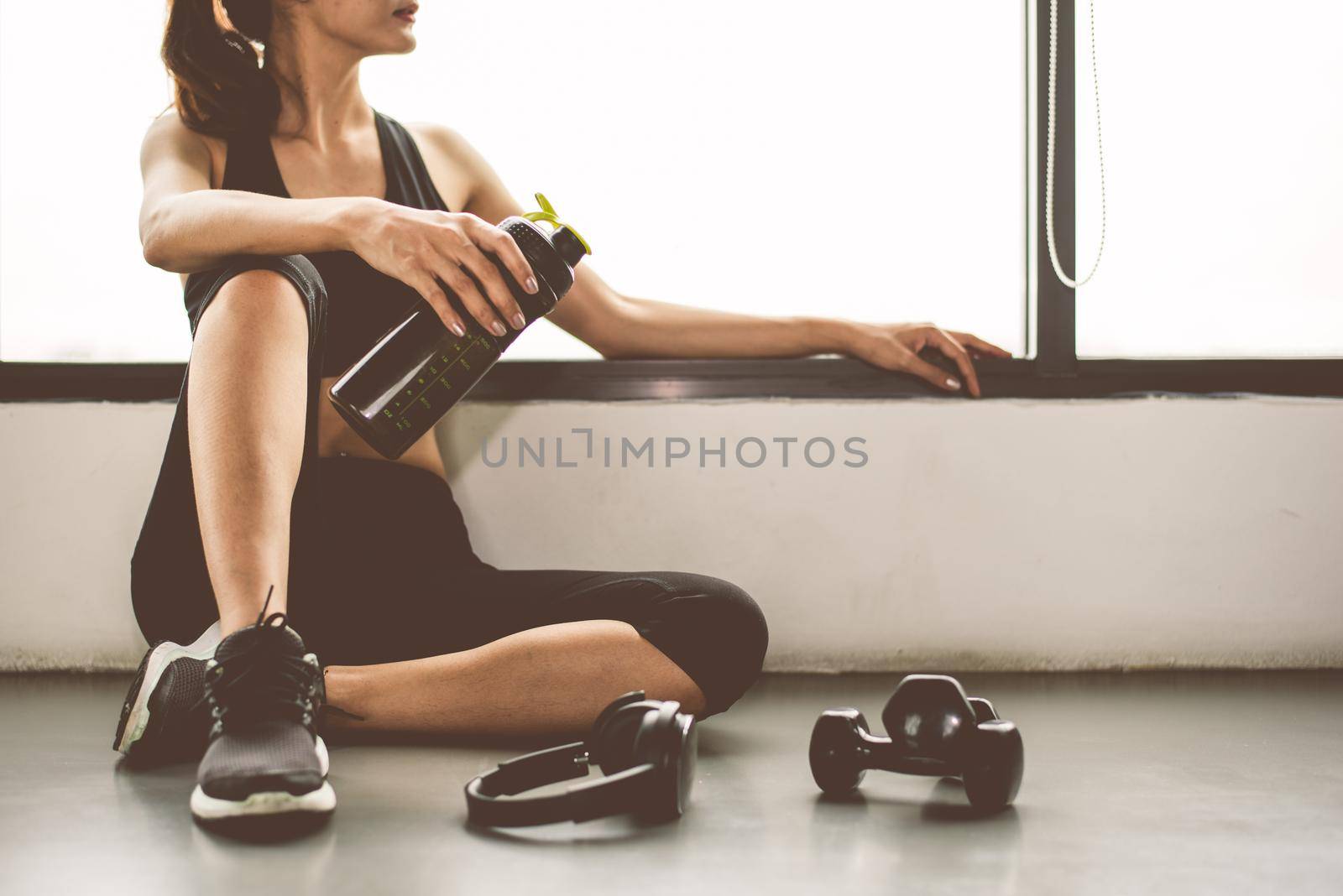 Woman with dumbbell and device exercise lifestyle workout in gym fitness breaking relax after sport training with protein shake bottle background. Healthy lifestyle bodybuilding and athlete muscles