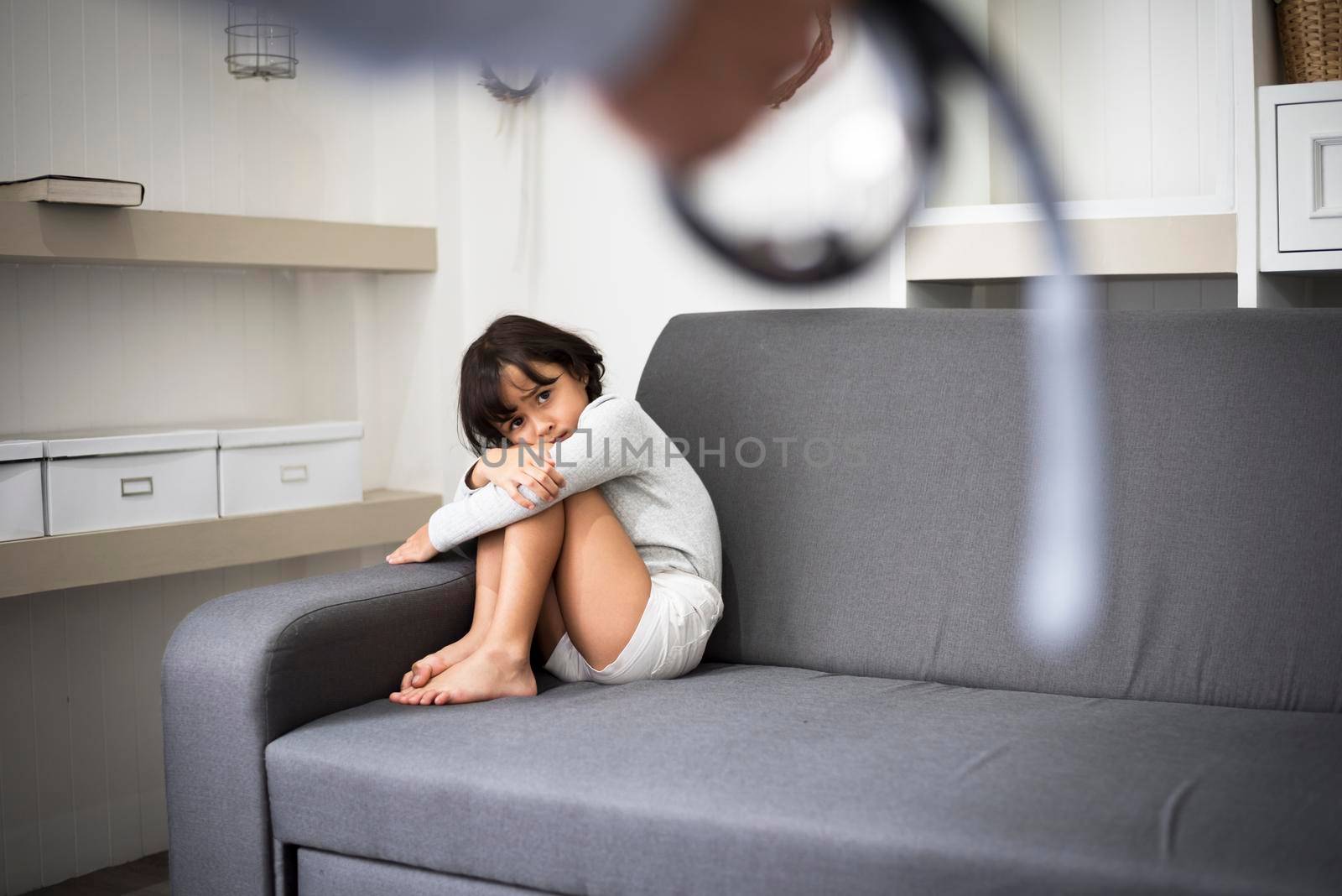 Little girl fearing her parents from punishing on sofa in dramatice moment.Children's Rights in Early Childhood Education and Social and parrents care problem concept