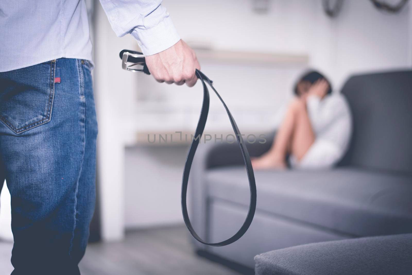 Selective focus of belt in stressed man hand against abstract blur of a little girl fearing in dramatic moment. Children's Rights in Early Childhood Education and Social parents care problem concept