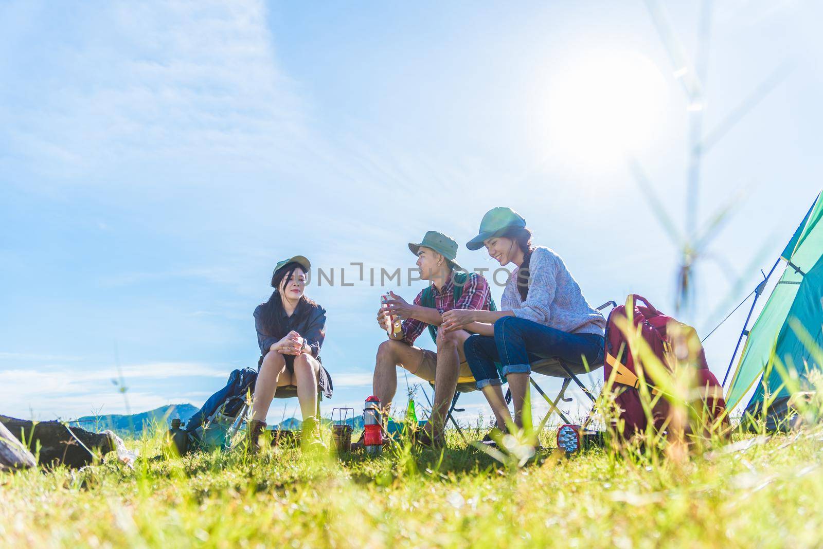 Group of travelers camping and doing picnic in meadow field foreground. Mountain and lake background. People and lifestyles concept. Outdoors activity and leisure theme. Backpacker and Hiker lifestyle