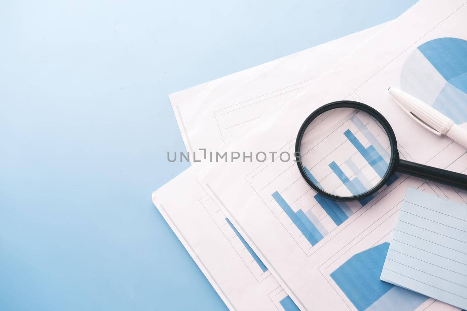 financial data and magnifying glass on blue . by towfiq007