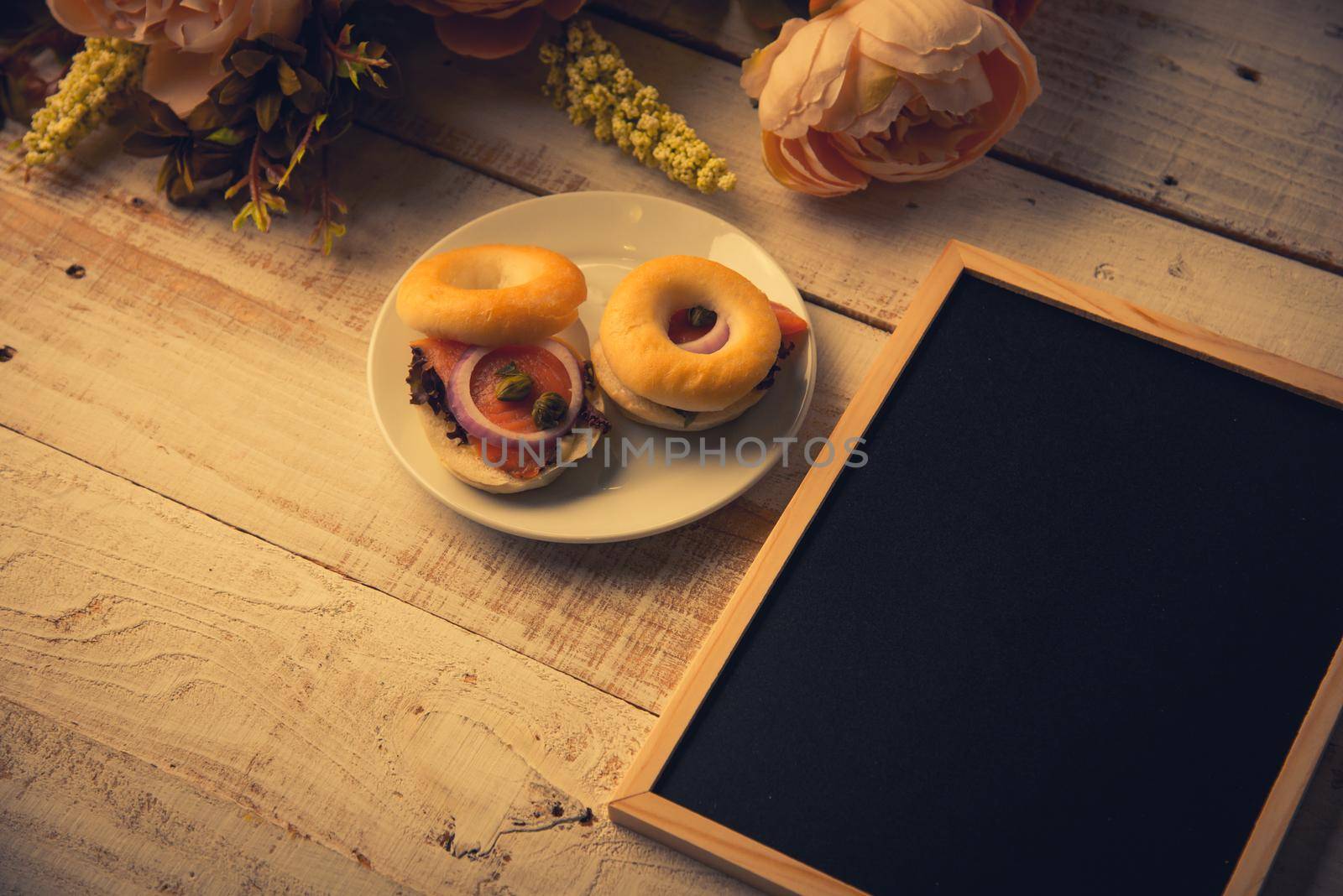 School empty wooden blackboard on wooden floor with hamburger bread and dry flowers. Education and Nature concept. Back to school theme.