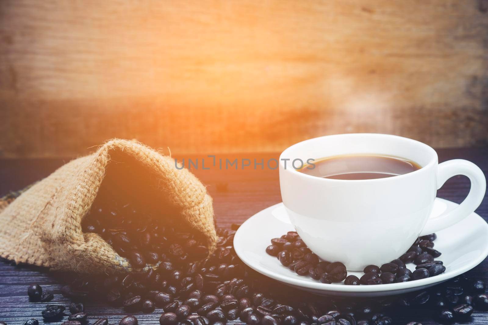 Side view of Coffee cup with  smoke and coffee beans in sack on wood table, Drinks and relax concept, for advertising