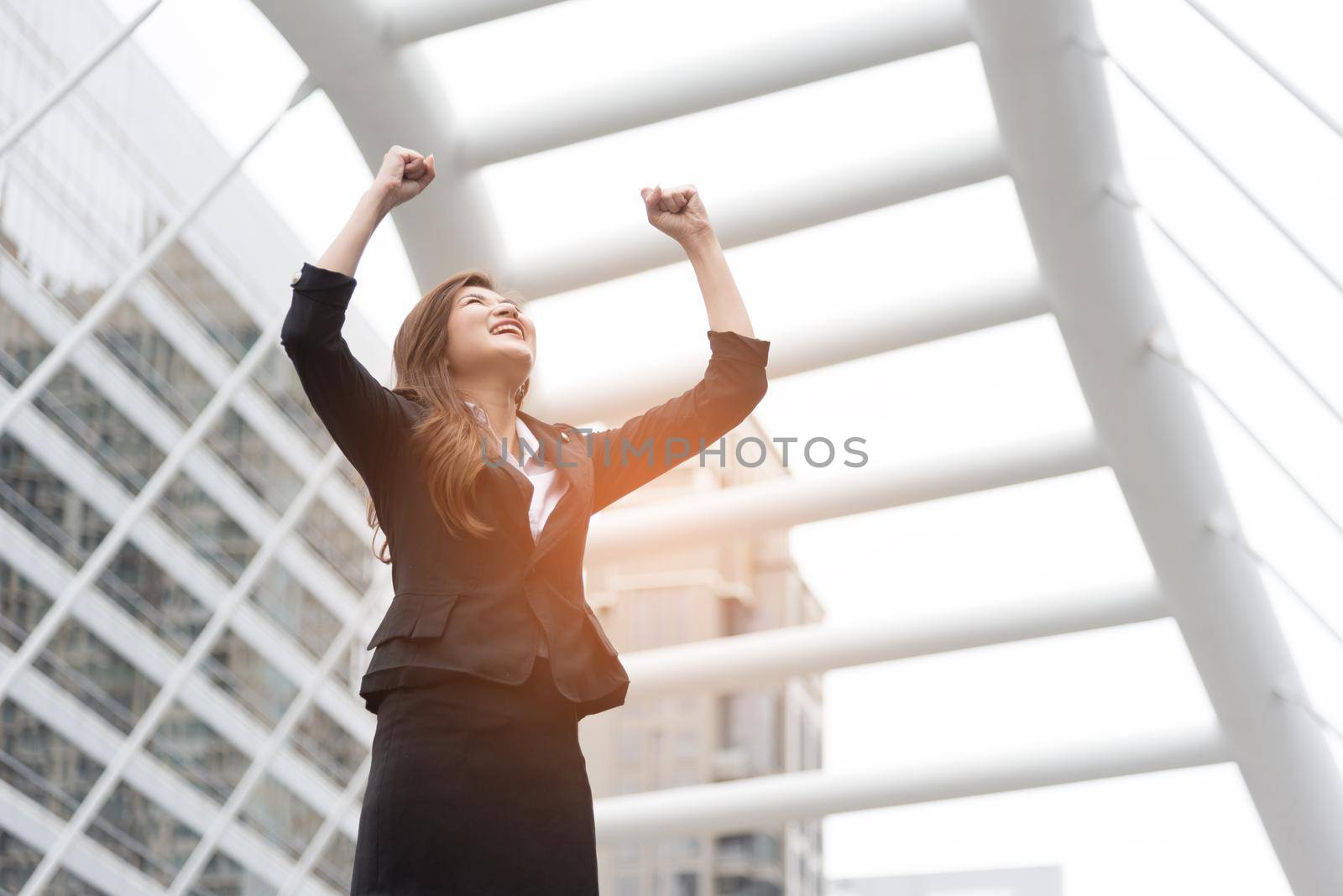 Happy business woman raise her hands at outdoors. Goal and successful concept. City and urban background