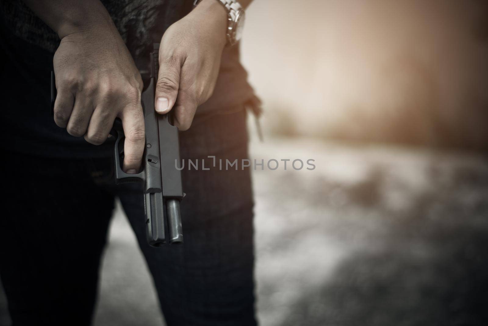 Robber holding gun for ready to murder steal moneys at abandoned building. Selective focus. criminality and social issues concept. Dark and low key tone tone pinterest and instragram like process.