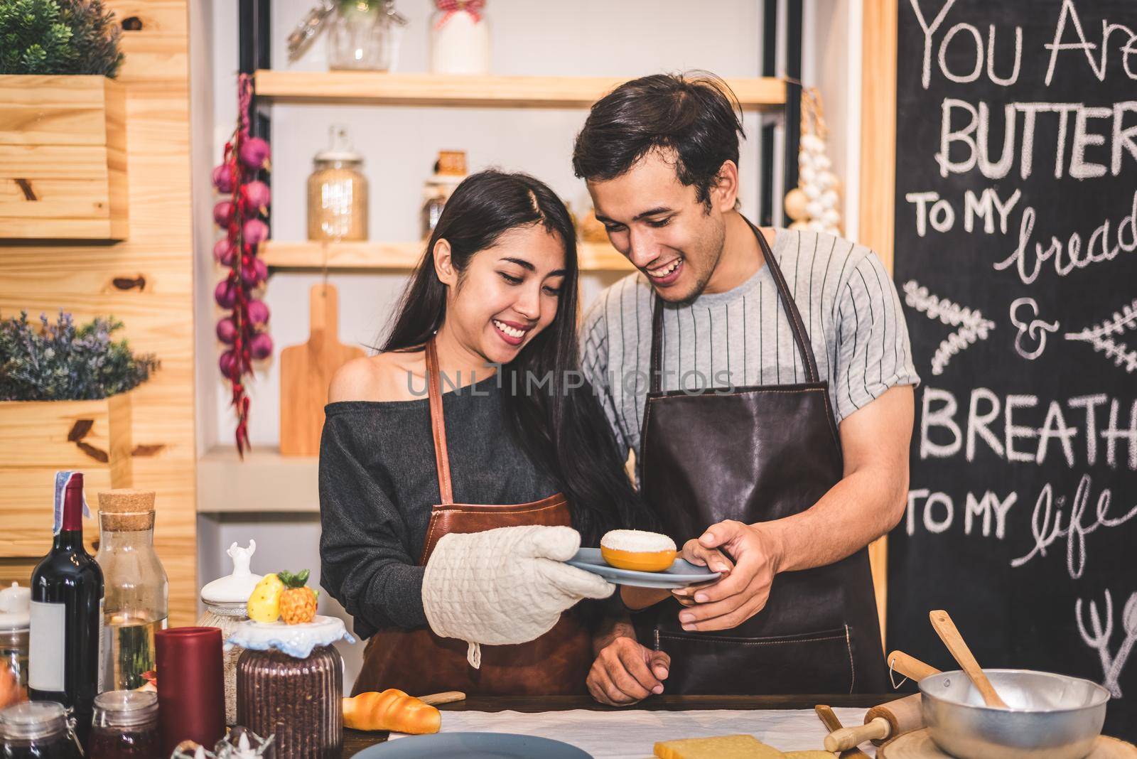 Young couples making bakery donuts and bread at bakery shop as business ownership entrepreneur. Husband and wife cooking together in kitchen. Happiness people and lifestyle relationship concept