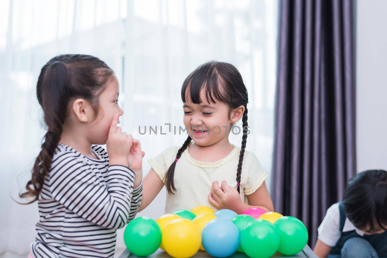 Two little girls and boy playing small toy balls in home together. Education and Happiness lifestyle concept. Funny learning and Children development theme. Smile faces by MiniStocker