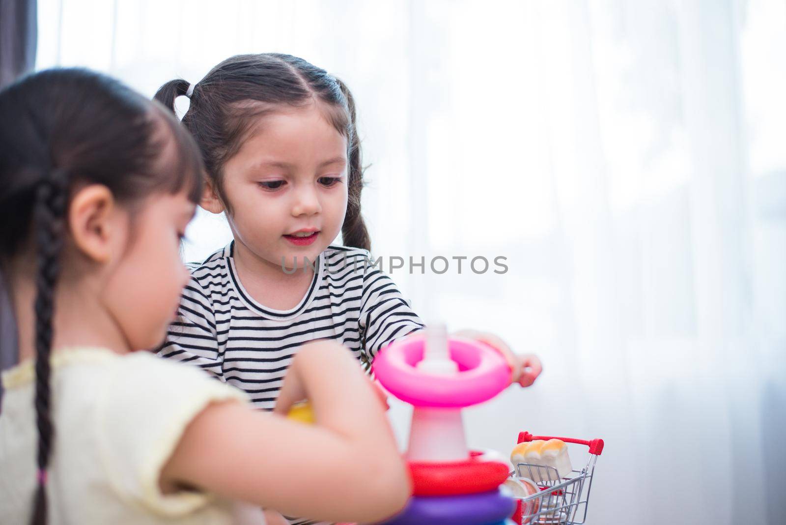 Two little girls playing toy hoops in home together. Education and Happiness lifestyle concept. Funny learning and Children development theme. Smile faces by MiniStocker