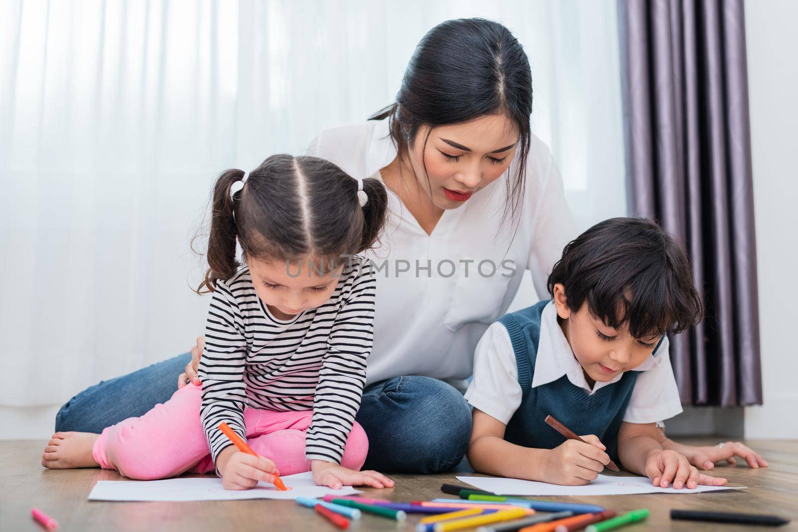 Mother teaching children in drawing class. Daughter and son painting with colorful crayon color in home. Teacher training students in art classroom. Education and Learning development of kids theme. by MiniStocker