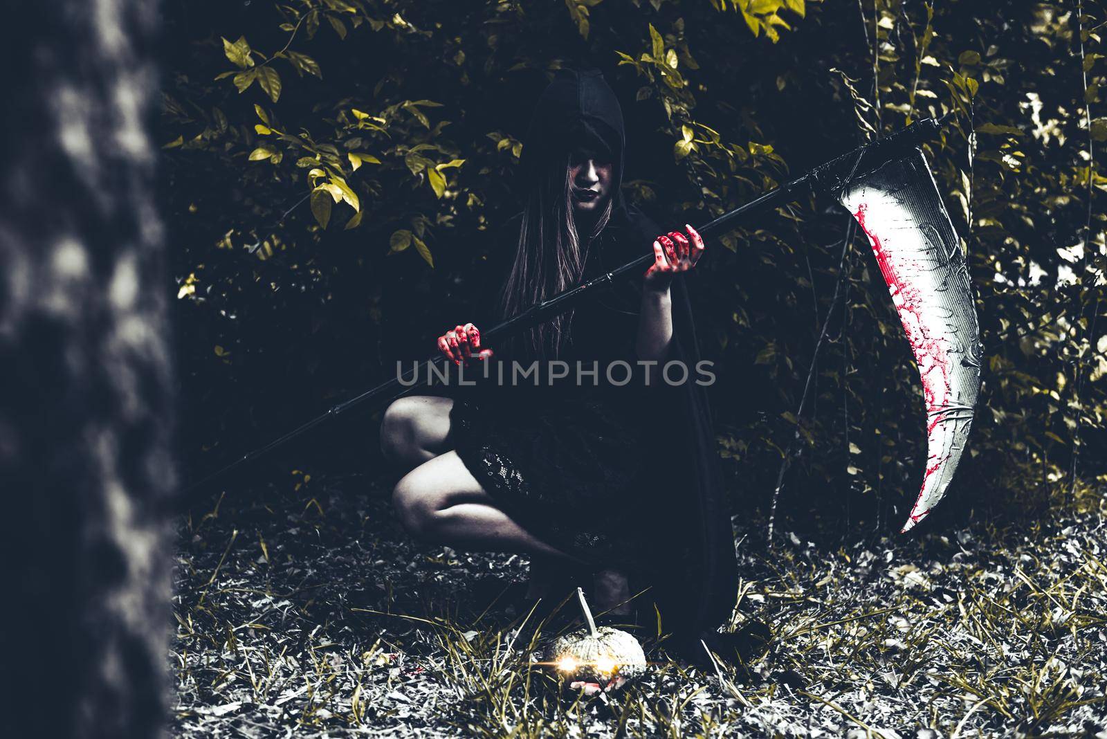 Demon witch sitting and holding reaper in black forest. Halloween day concept. by MiniStocker