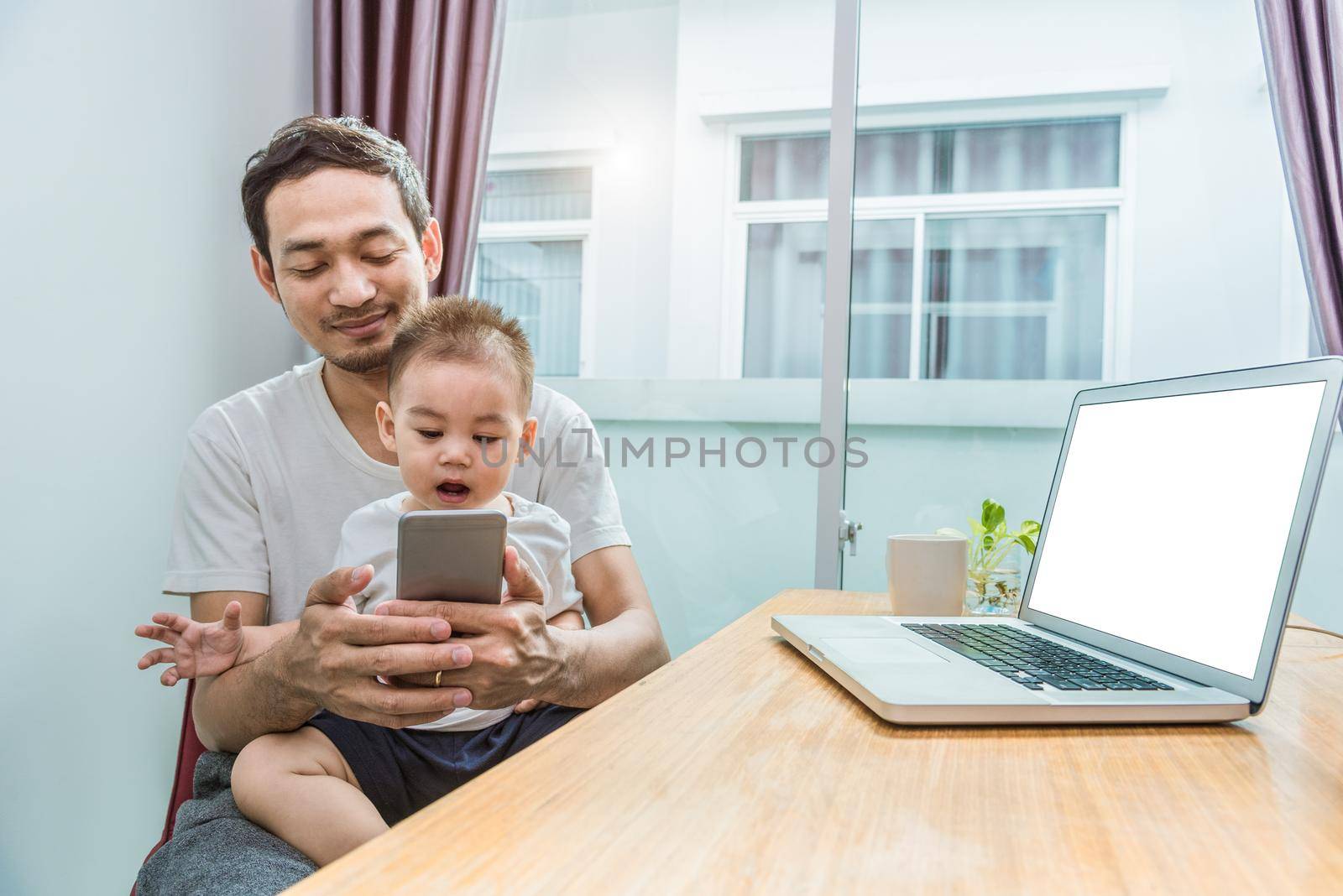 Asian father and son using smart phone together in home background. Technology and People concept. Lifestyles and Happy family theme. Internet and communication theme by MiniStocker