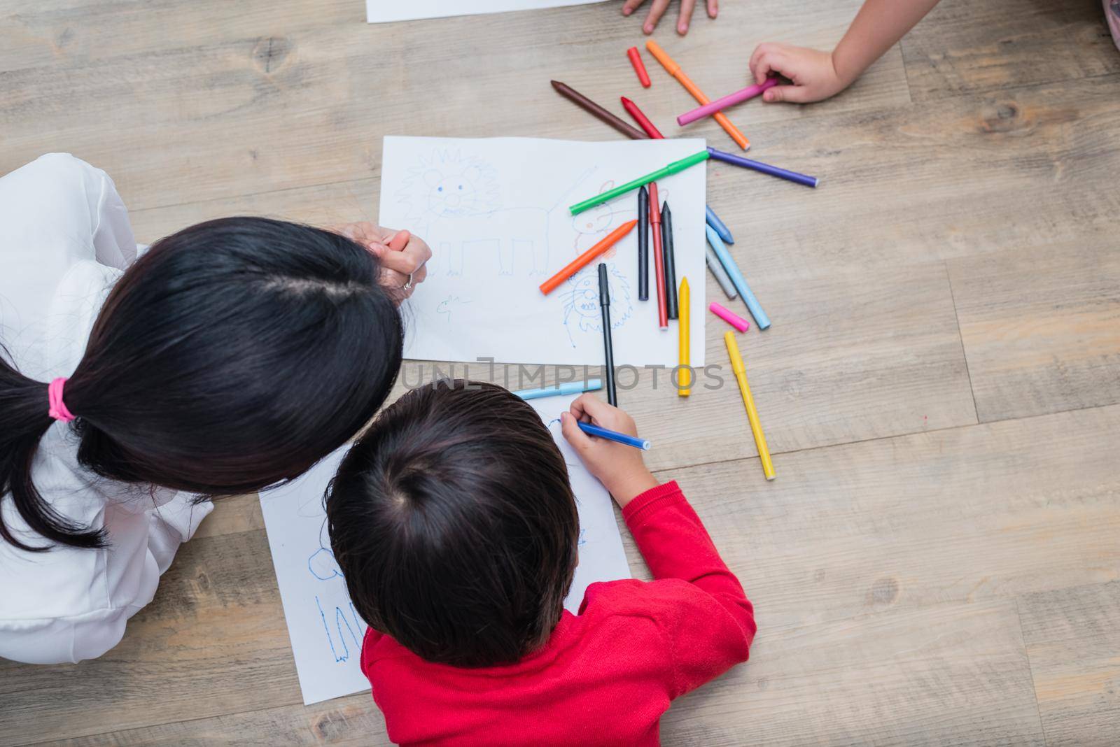 Group of preschool student and teacher drawing on paper in art class. Back to school and Education concept. People and lifestyles theme.  Room in nursery