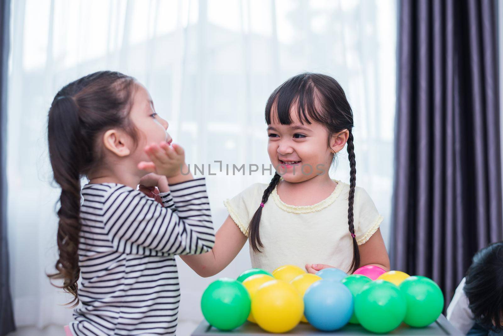 Two little girls playing small toy balls in home together. Education and Happiness lifestyle concept. Funny learning and Children development theme. Smile faces