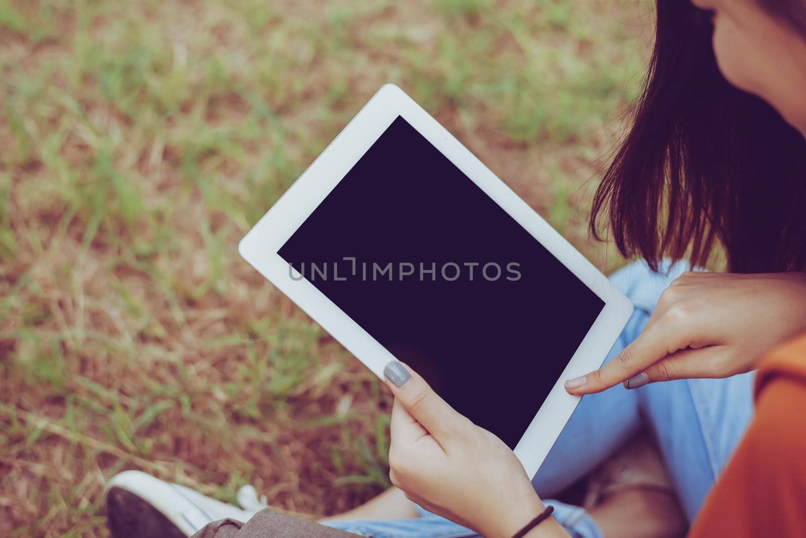 Beauty Asian woman using tablet at park. People and Technology concept. Leisure and Outdoor activity theme.