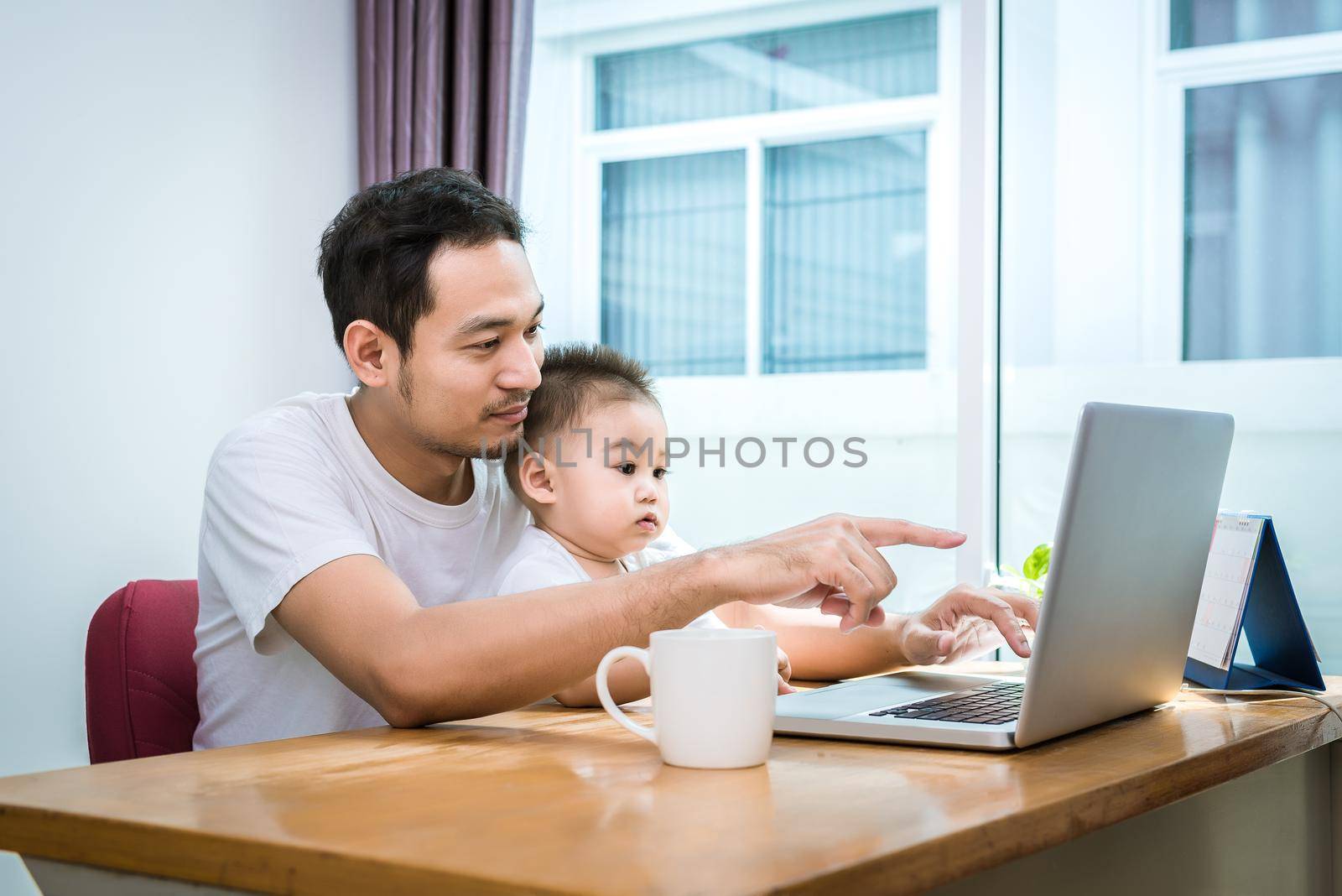 Single dad and son using laptop together happily. Technology and Lifestyles concept. Happy family and baby theme.