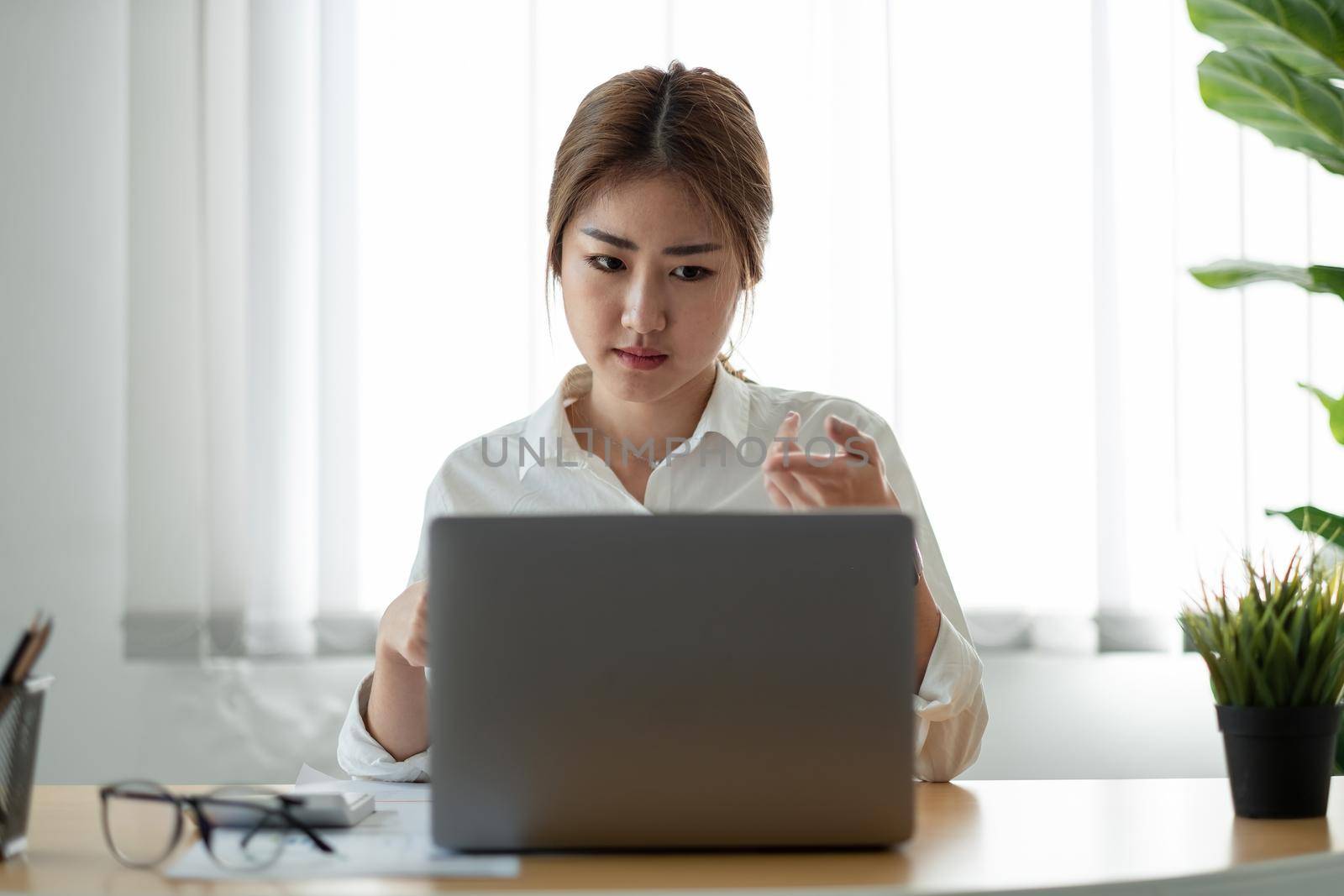 Asian woman watching educational webinar on laptop. Smiling young businessman holding video call with clients partners by nateemee