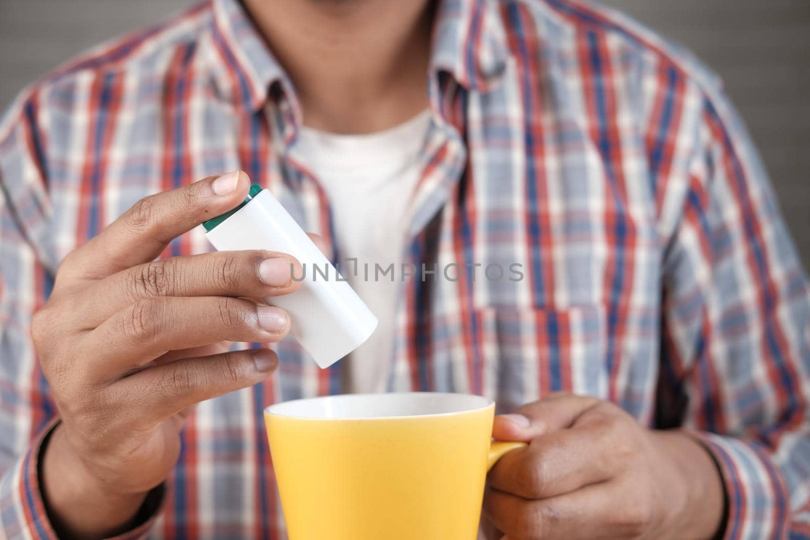 young man putting artificial sweetener in tea
