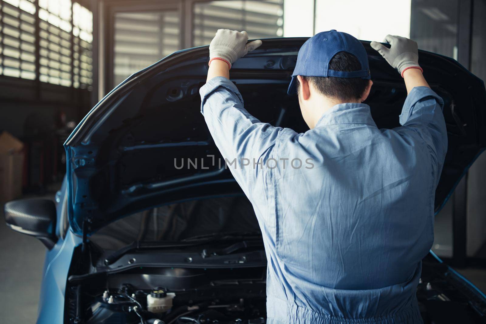 Car mechanic opening car hood for internal checking to maintenance vehicle by customer claim order in auto repair shop garage. Engine repair service. People occupation and job. Automobile technician