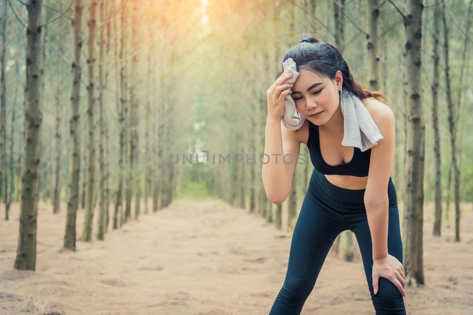 Asian beauty woman wiping the sweat in forest. Towel and sweat elements. Sport and Healthy concept. Jogging and Running concept. Relax and take a break theme. Outdoors activity theme.