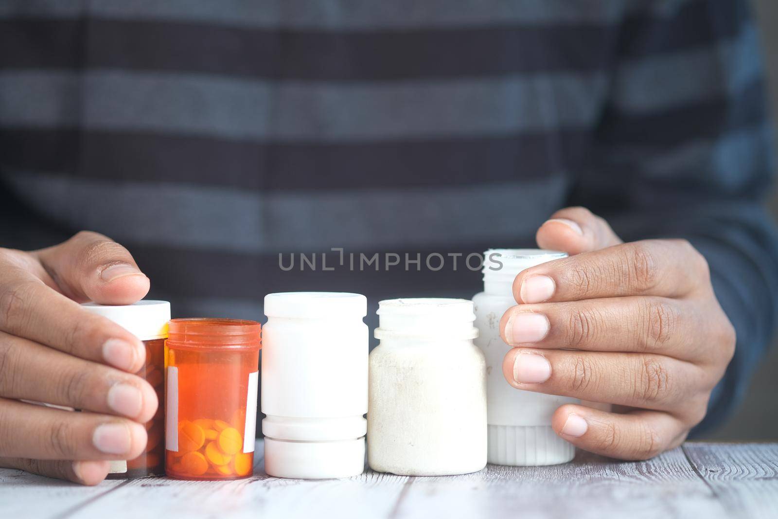 young man hand holding many medicine pill container white sited ,