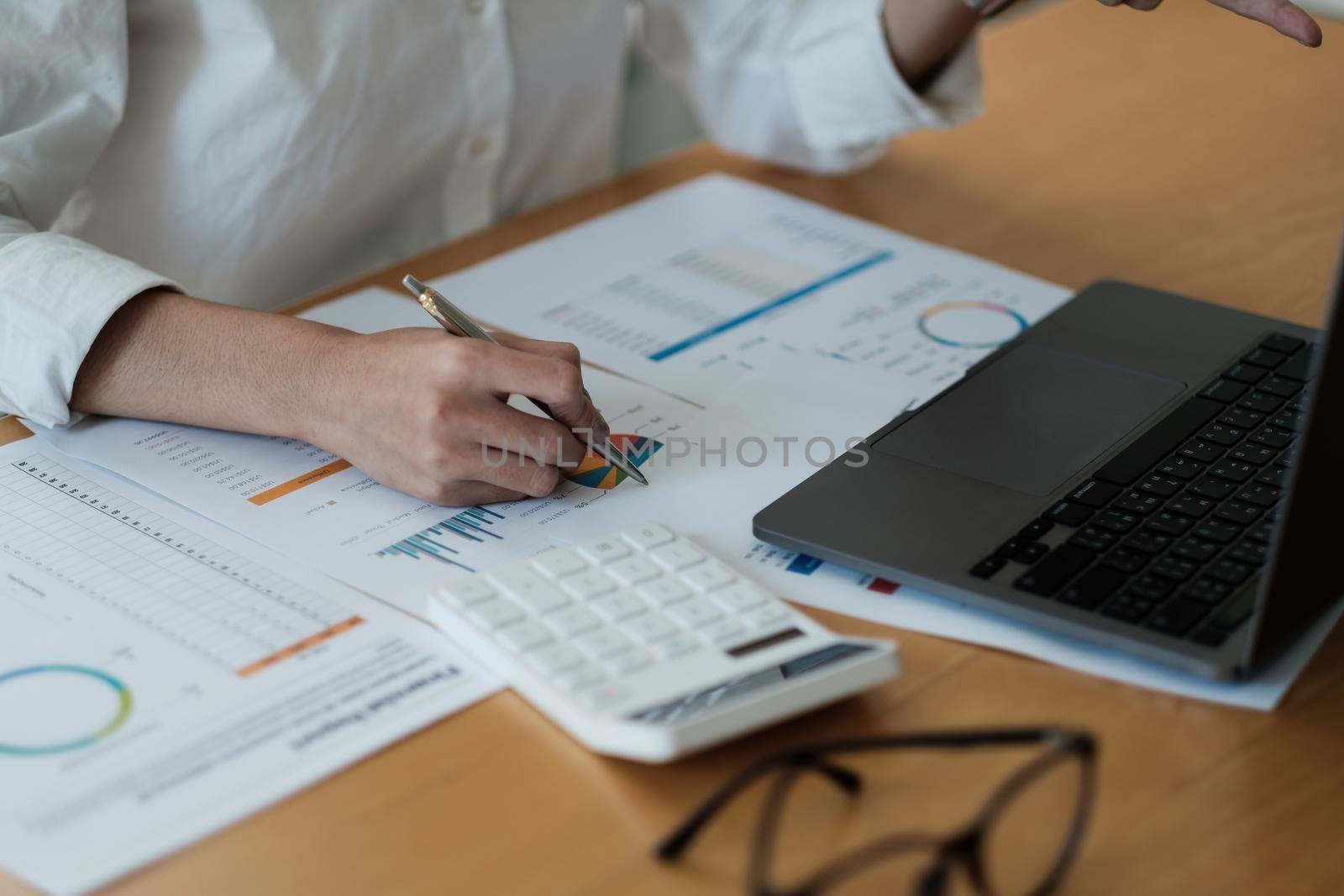 Woman accountant use calculator and computer analytic marketing report on wooden desk in office. finance and accounting concept. by nateemee