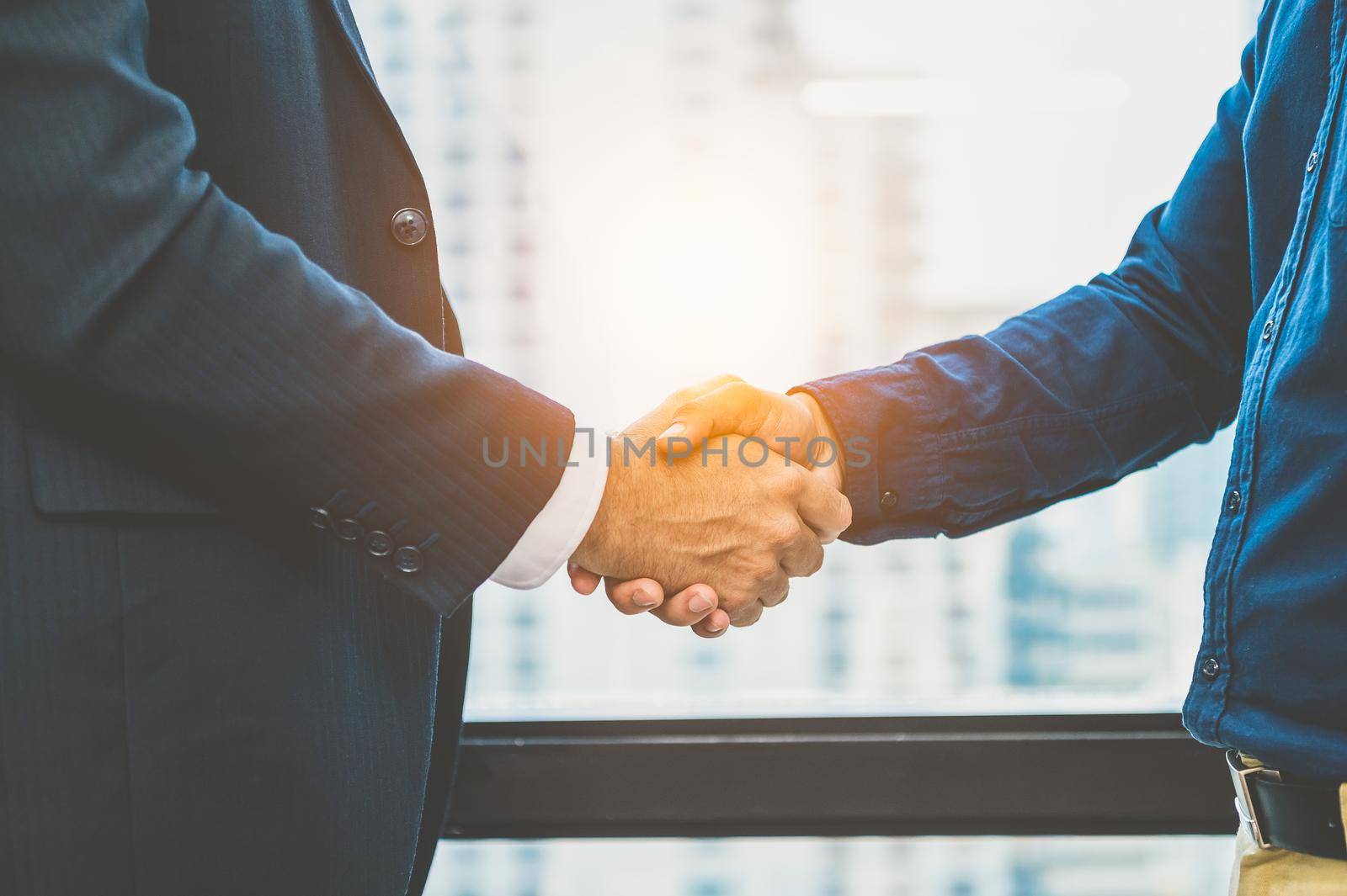 Business partnership meeting handshaking concept. Businessmen doing handshake. Successful business people contract handshaking after finished good dealing with skyscraper window building background.
