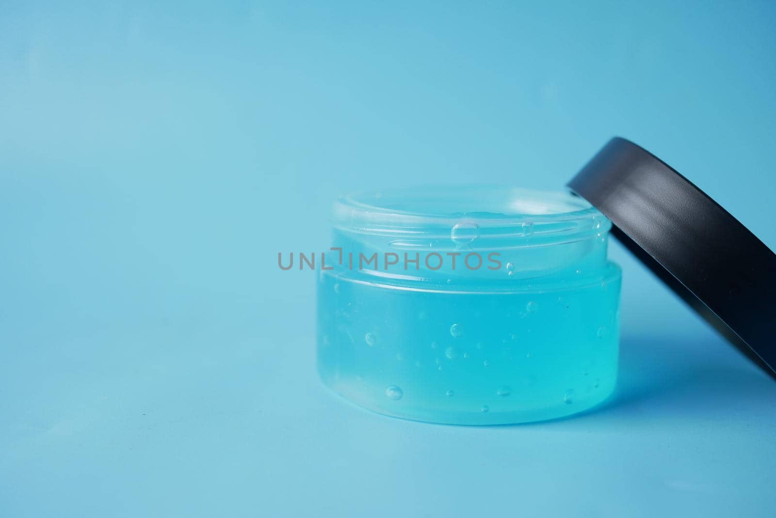 a jar of hair gel on blue background with copy space by towfiq007