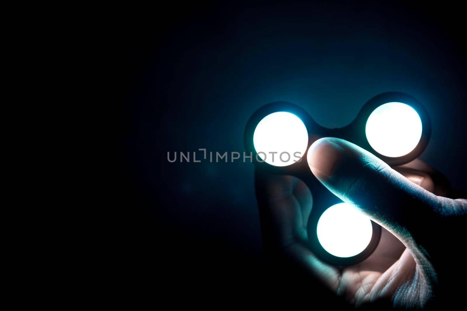 Fidget spinner toy with neon light consist of ball-bearing made from metal or plastic helping people who have trouble with focusing by relieving nervous energy or psychological stress. selective focus