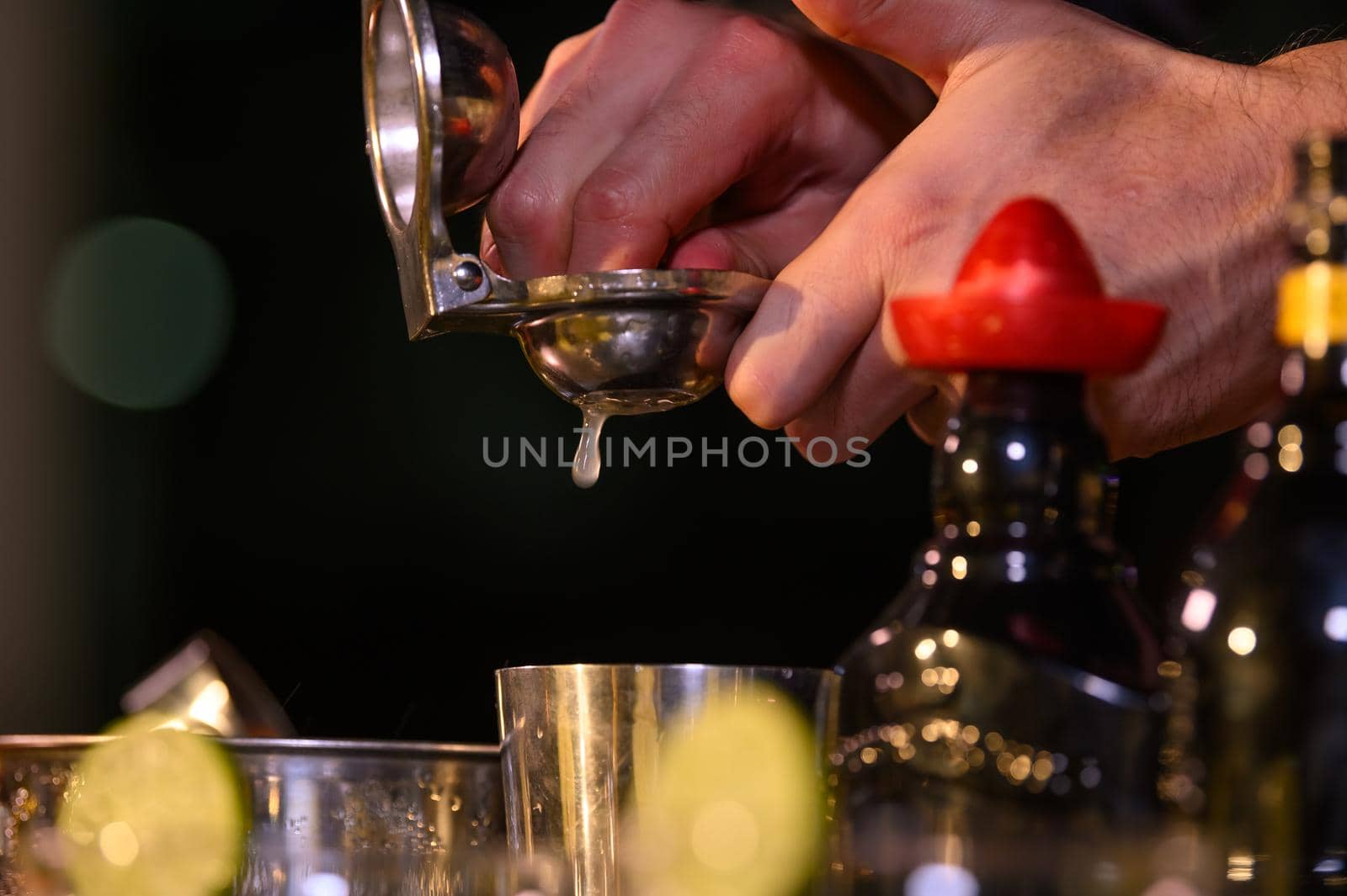 Closeup bartender hand preparing fresh juice cocktail in drinking wine glass with ice at night bar clubbing counter. Occupation and people lifestyles concept. Outdoor and nightclub background
