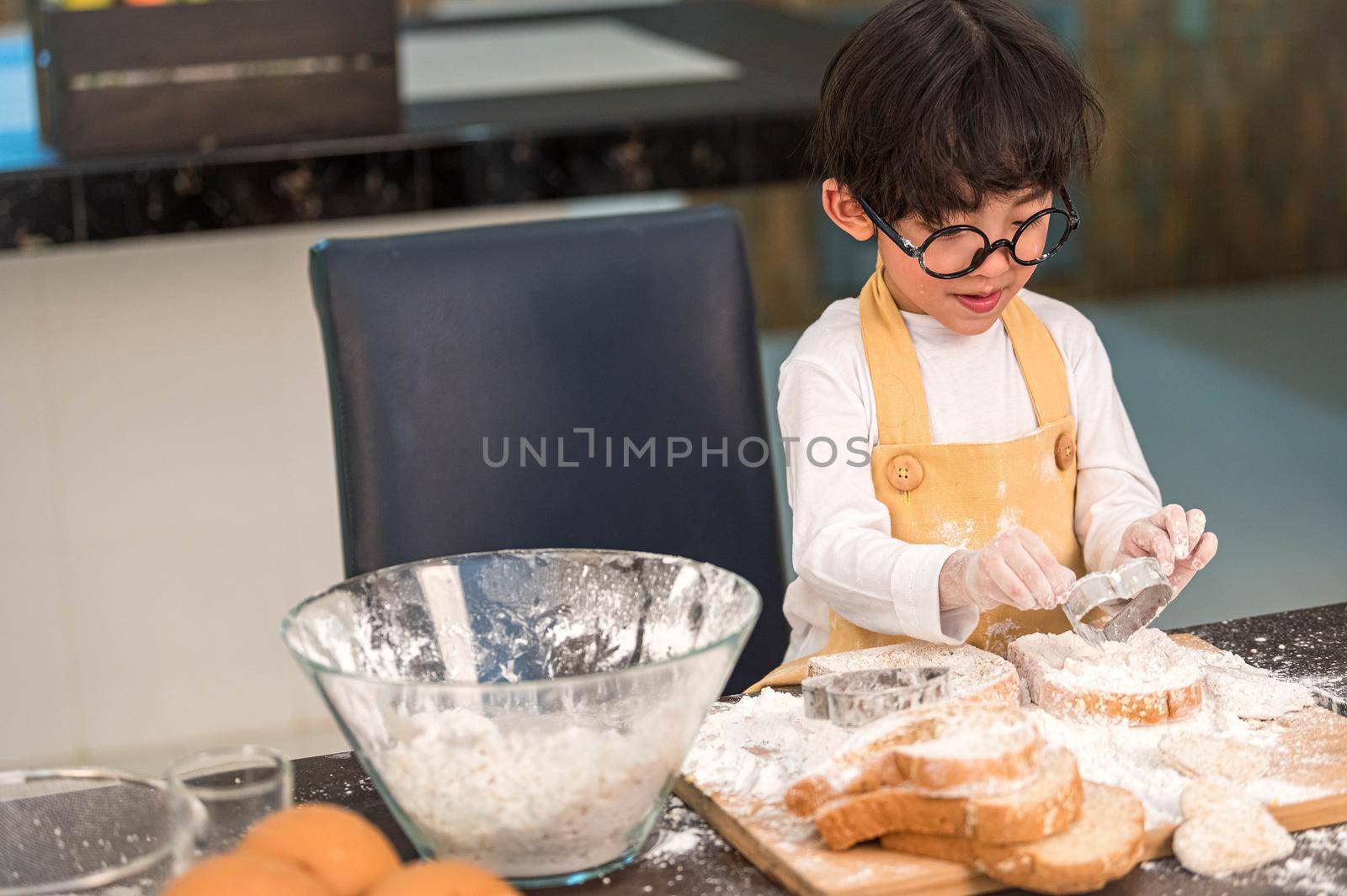 Portrait cute little Asian happiness boy interested in baking bakery with funny in home kitchen. People lifestyles and Family. Homemade food and ingredients concept. Baking Christmas cake and cookies