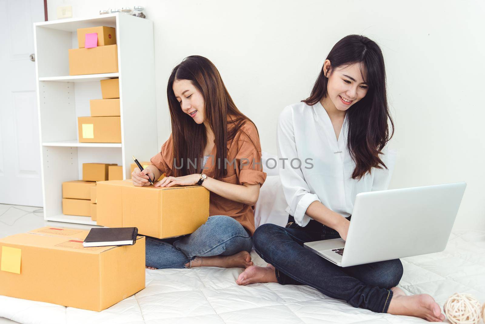 Young Asian woman startup small business entrepreneur SME distribution warehouse with parcel mail box. Owner home office concept. Online marketing and product packaging and delivery service. by MiniStocker
