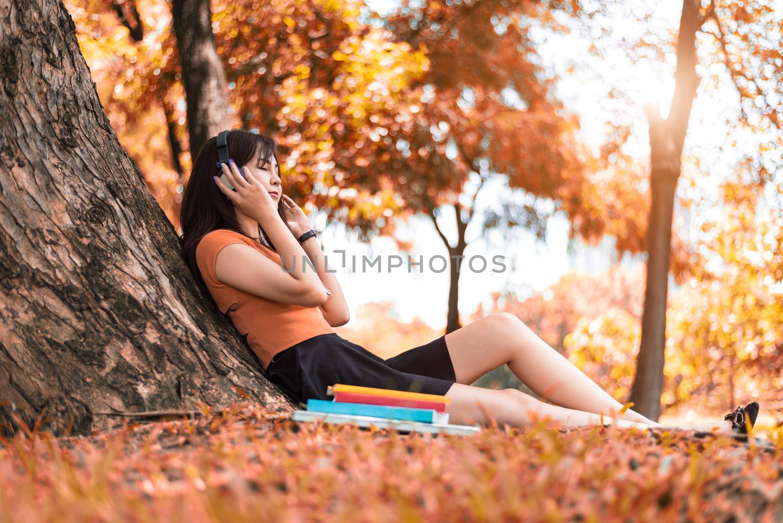 Asian beauty woman listen to the music in park. People lifestyles and Entertainment concept. Relaxation and Vacation concept. Autumn and fall seasonal theme.