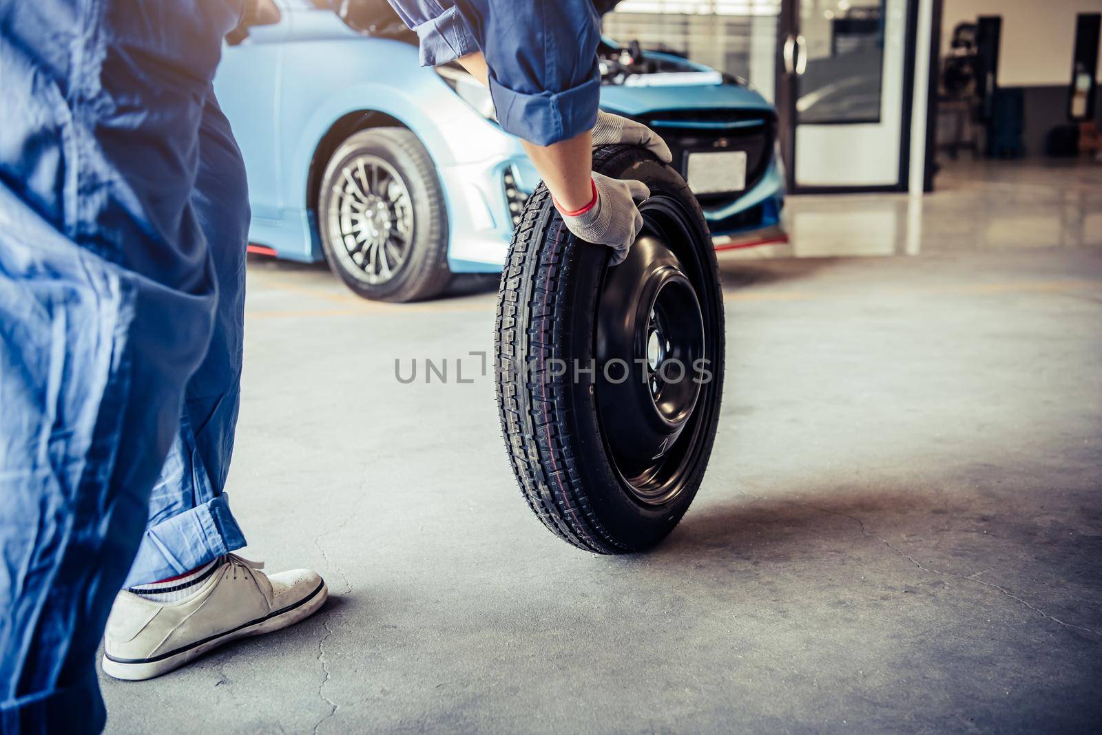 Car mechanics changing tire at auto repair shop garage. Transportation and Business working people concept. Automobile technician maintenance vehicle by customer claim order. Wheel repair service