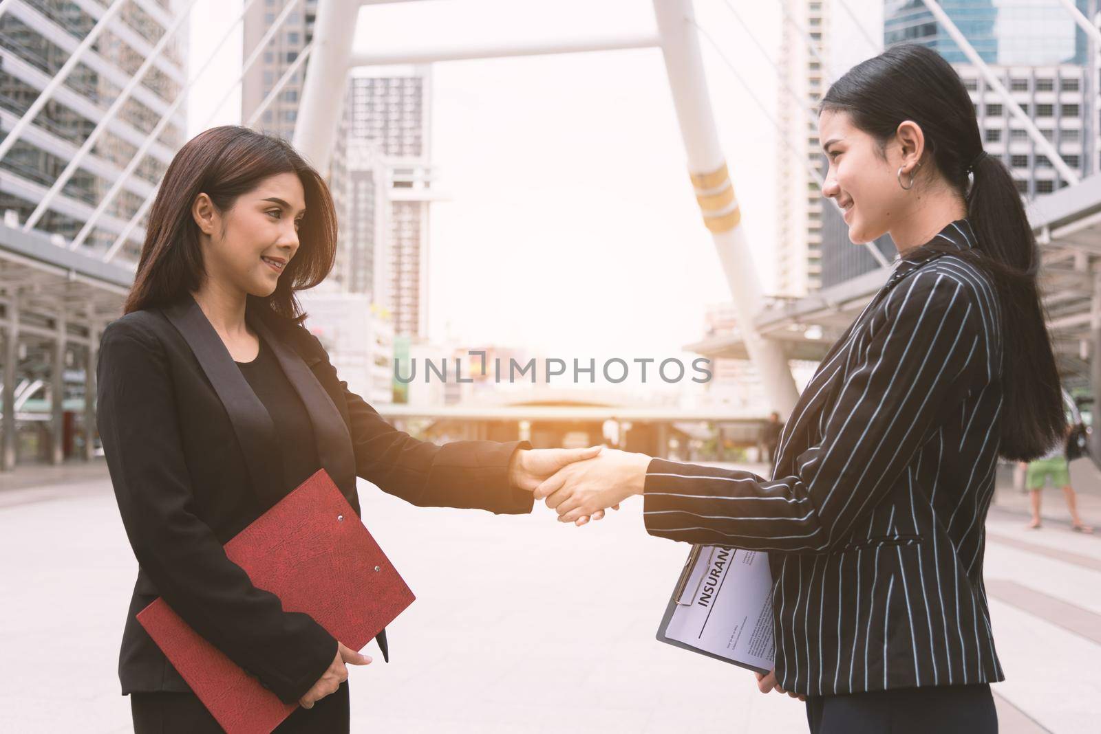 Two women making handshake greeting each other in group meeting at outdoors. Business people and deal contract. Friendship and Leadership concept.