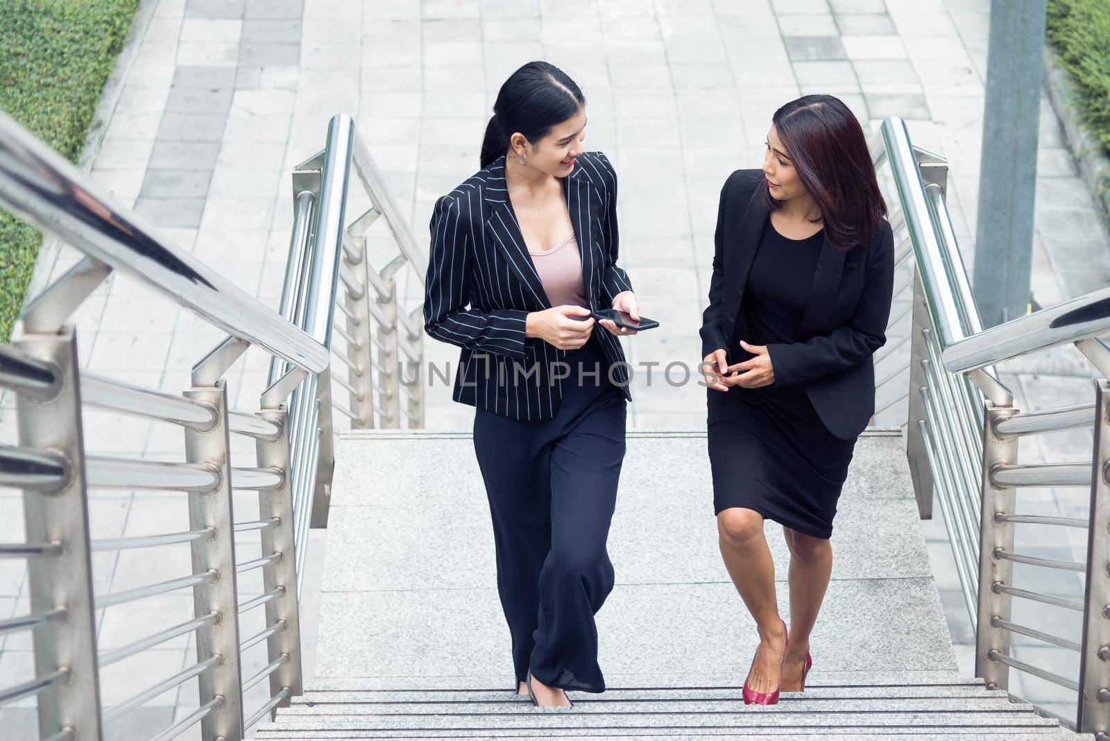 Two businesswomen walking up on stair and talking together. Business and work concept. Job and occupation concept.