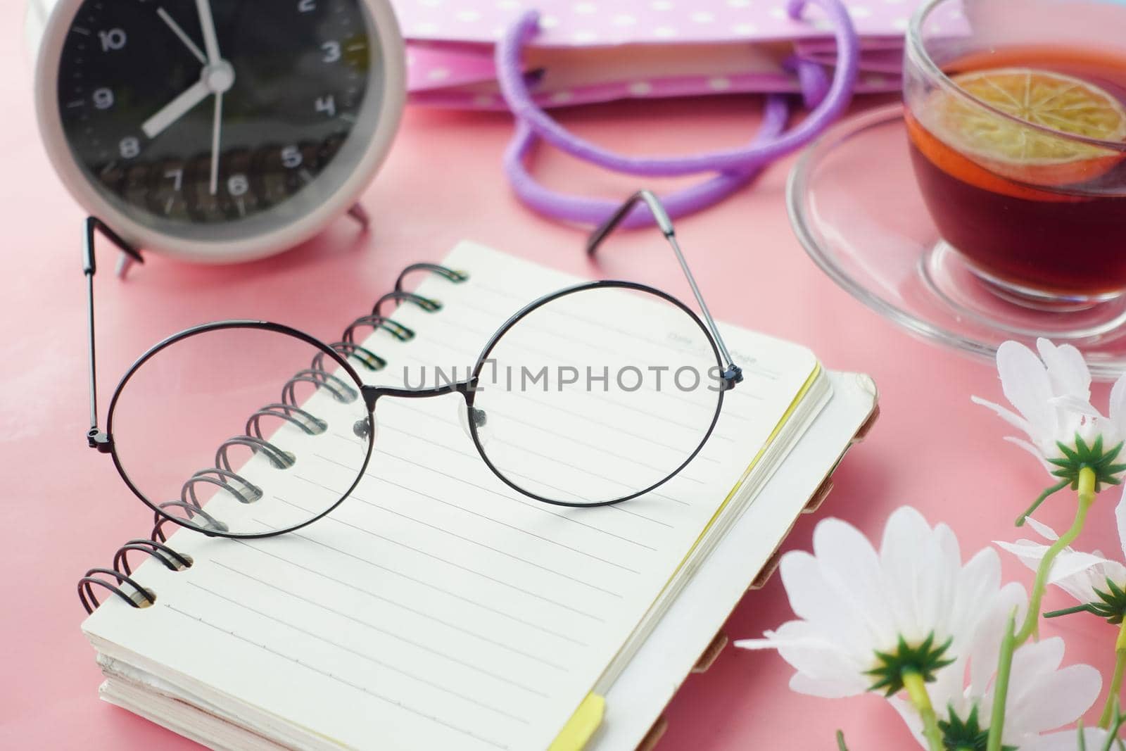 Old eyeglass on a notepad on pink background ,