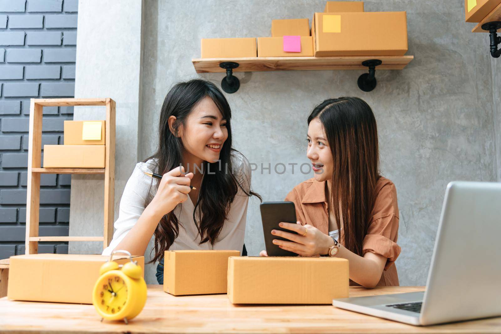 Two young Asian women startup small business entrepreneur SME distribution warehouse with parcel mail box. small  owner home office. Online marketing and product packaging and delivery service