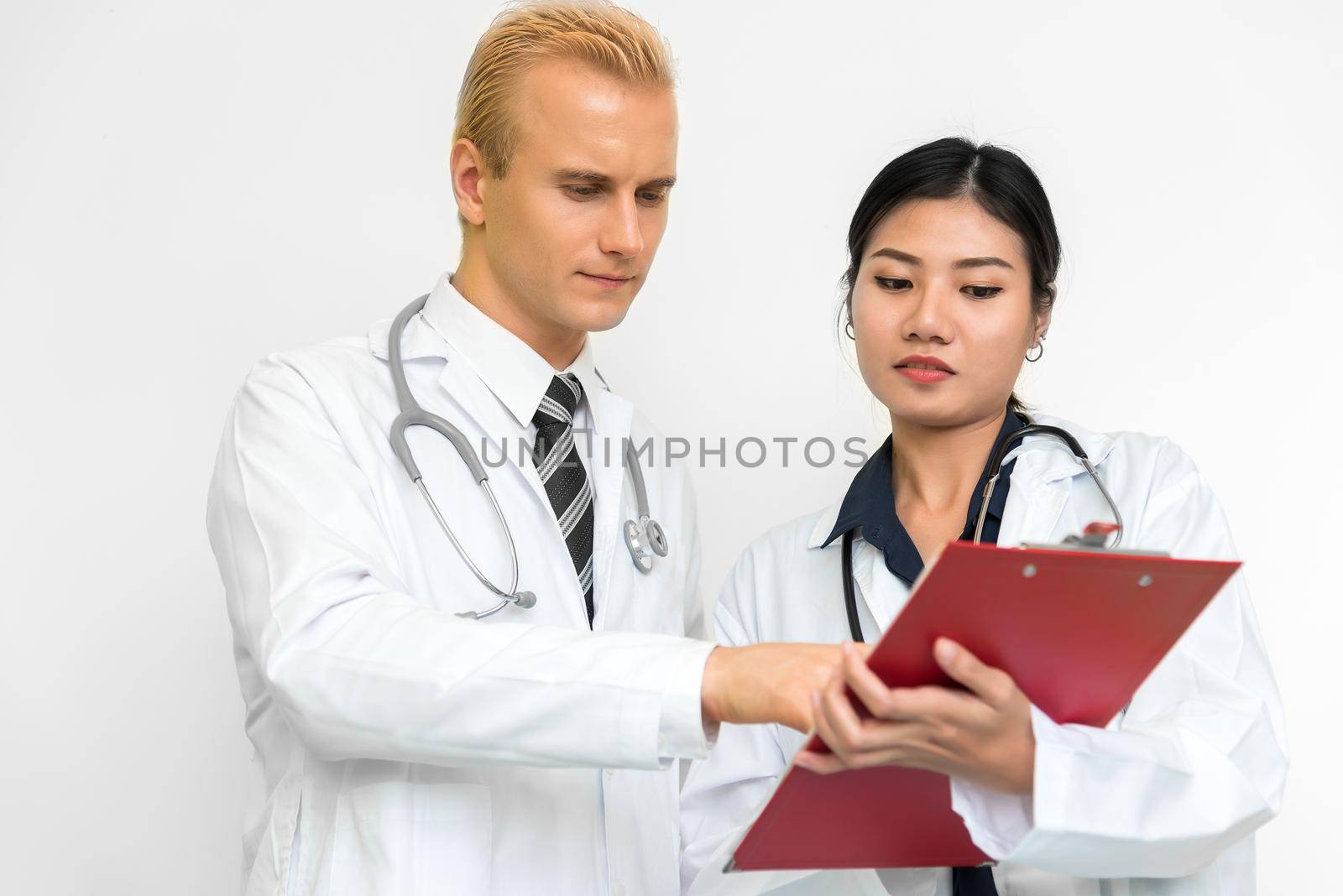 Doctor and assistant nurse checking patient laboratory test. Two hospital workers discussing on checking result list. Medical and Healthcare concept. People and Lifestyles theme. by MiniStocker