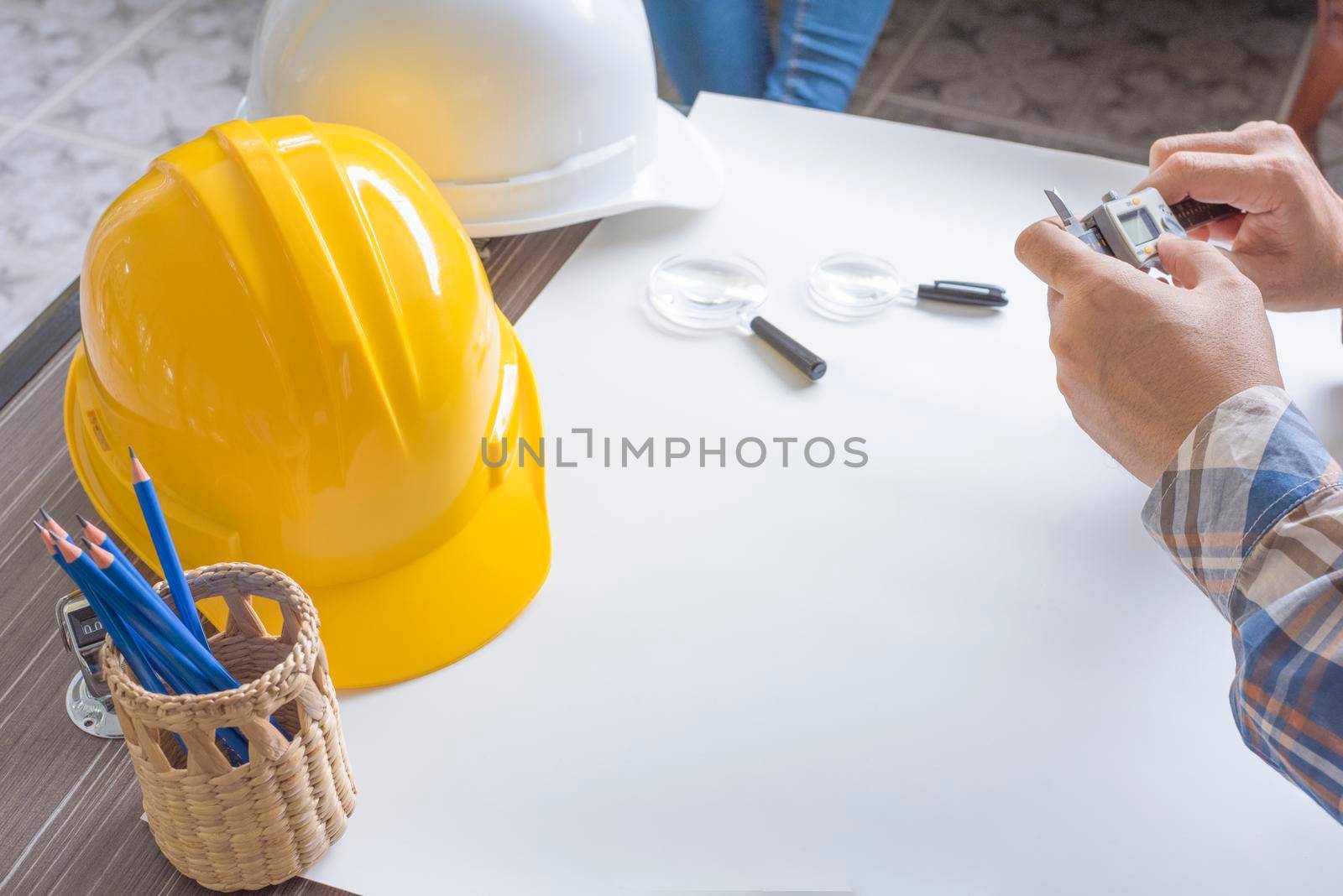 Construction engineer measuring with vernier caliper. Business and Technology concept. Safety helmet and Drawing paper elements. Civil and Drawing sketch theme.