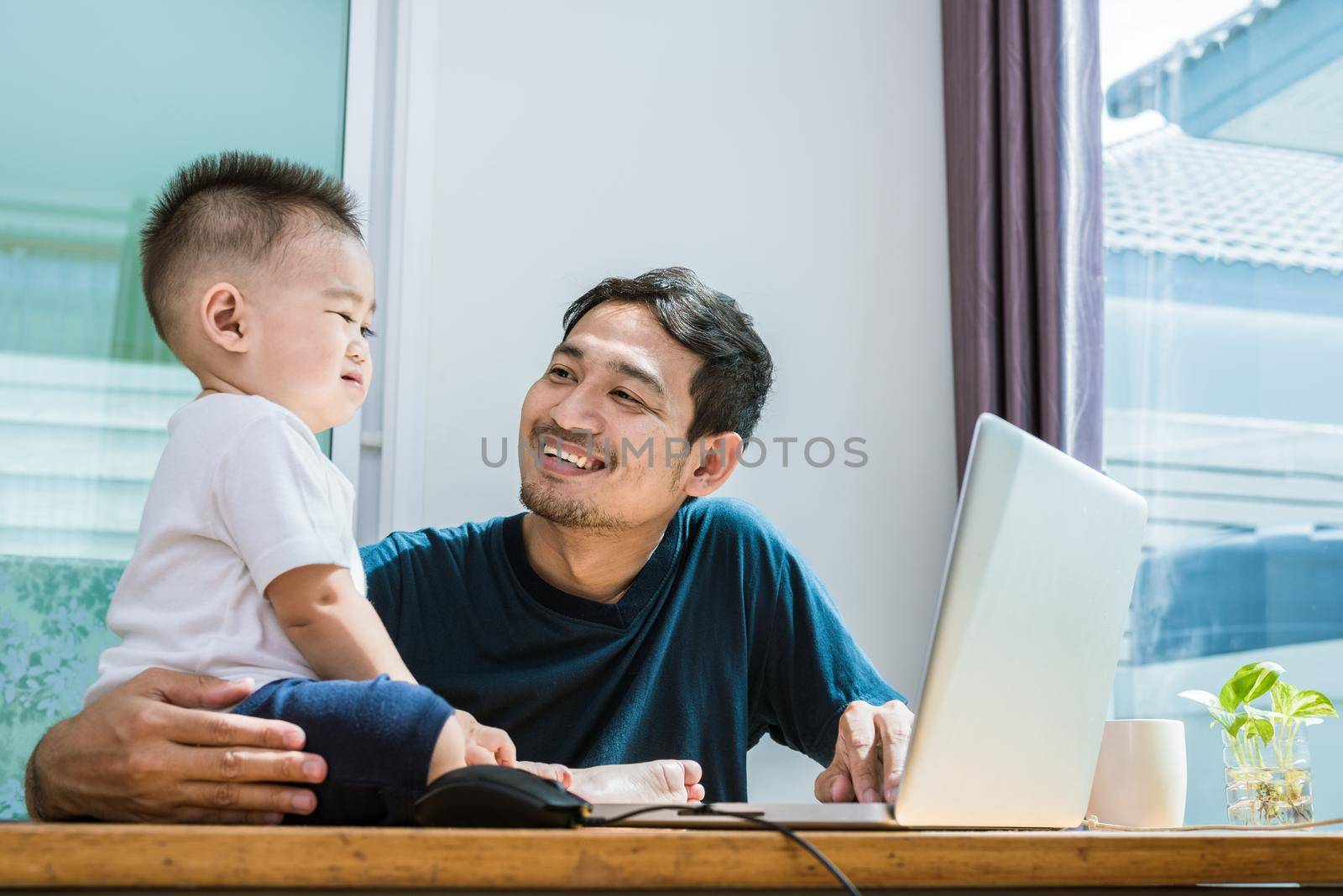 Single dad and son using laptop together happily. Technology and Lifestyles concept. Happy family and baby theme.