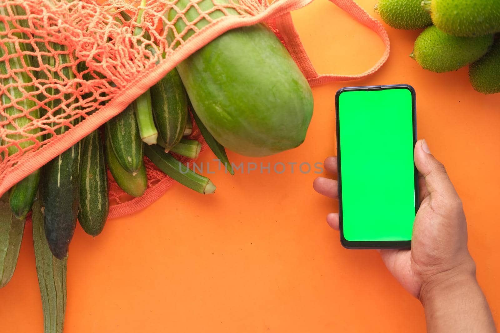 top view of man's hand holding smart phone with fresh vegetable on table by towfiq007