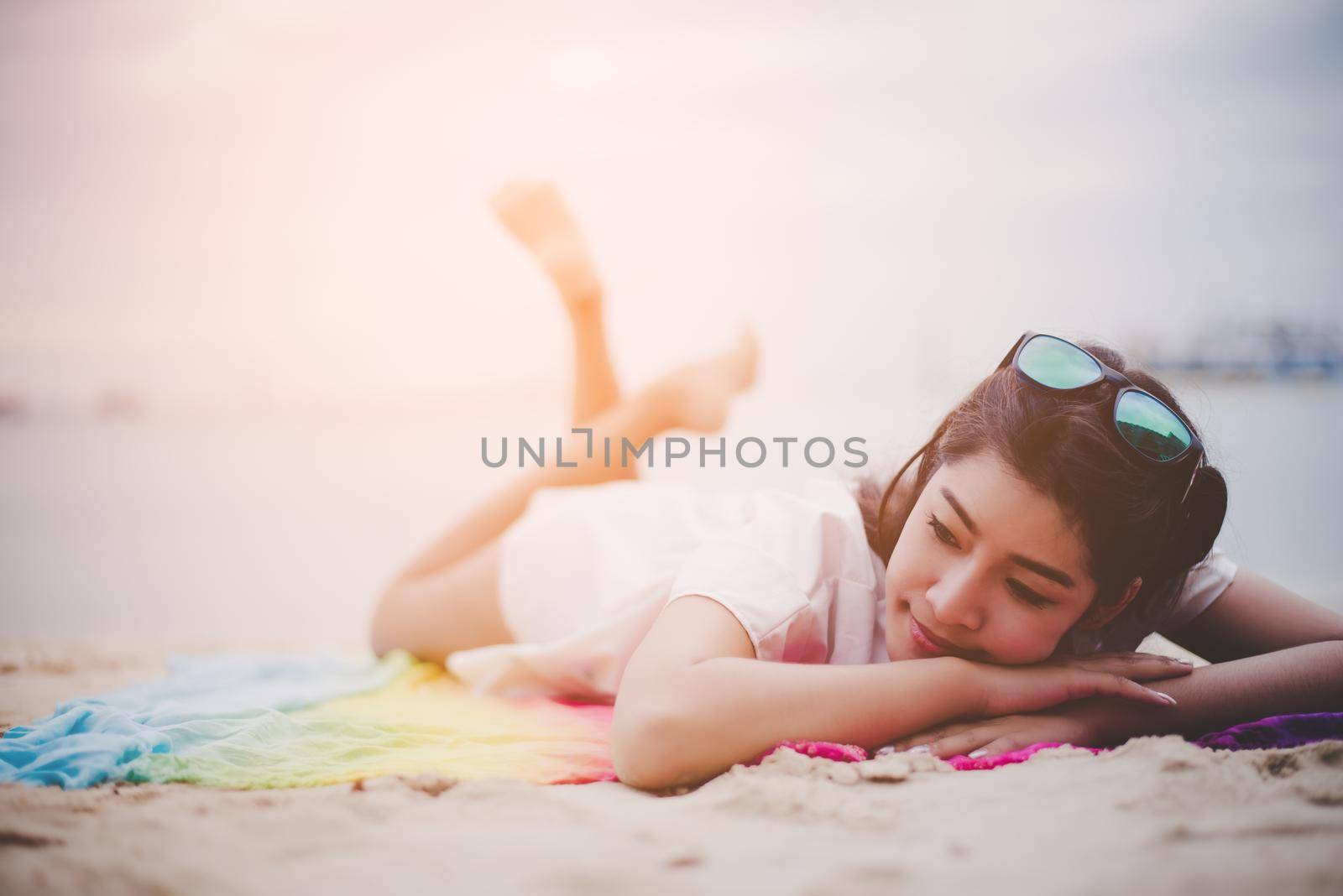 Beauty Asian woman have vacation on beach. Girl wearing sunglasses and lying on colorful mat near sea. Lifestyle and happy life concept.  Travel and holiday theme. Summer and tropical theme. by MiniStocker