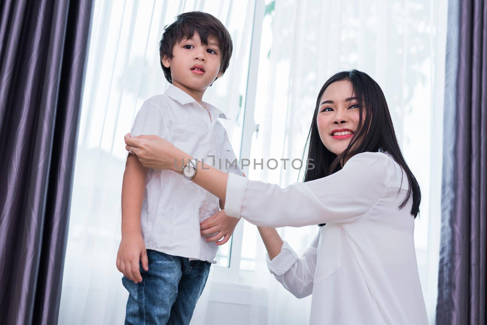 Young Asian mom dressed up son outfits for preparing go to school. Mother and son concept. Happy family and Home sweet home theme. Preschool and Back to school theme.