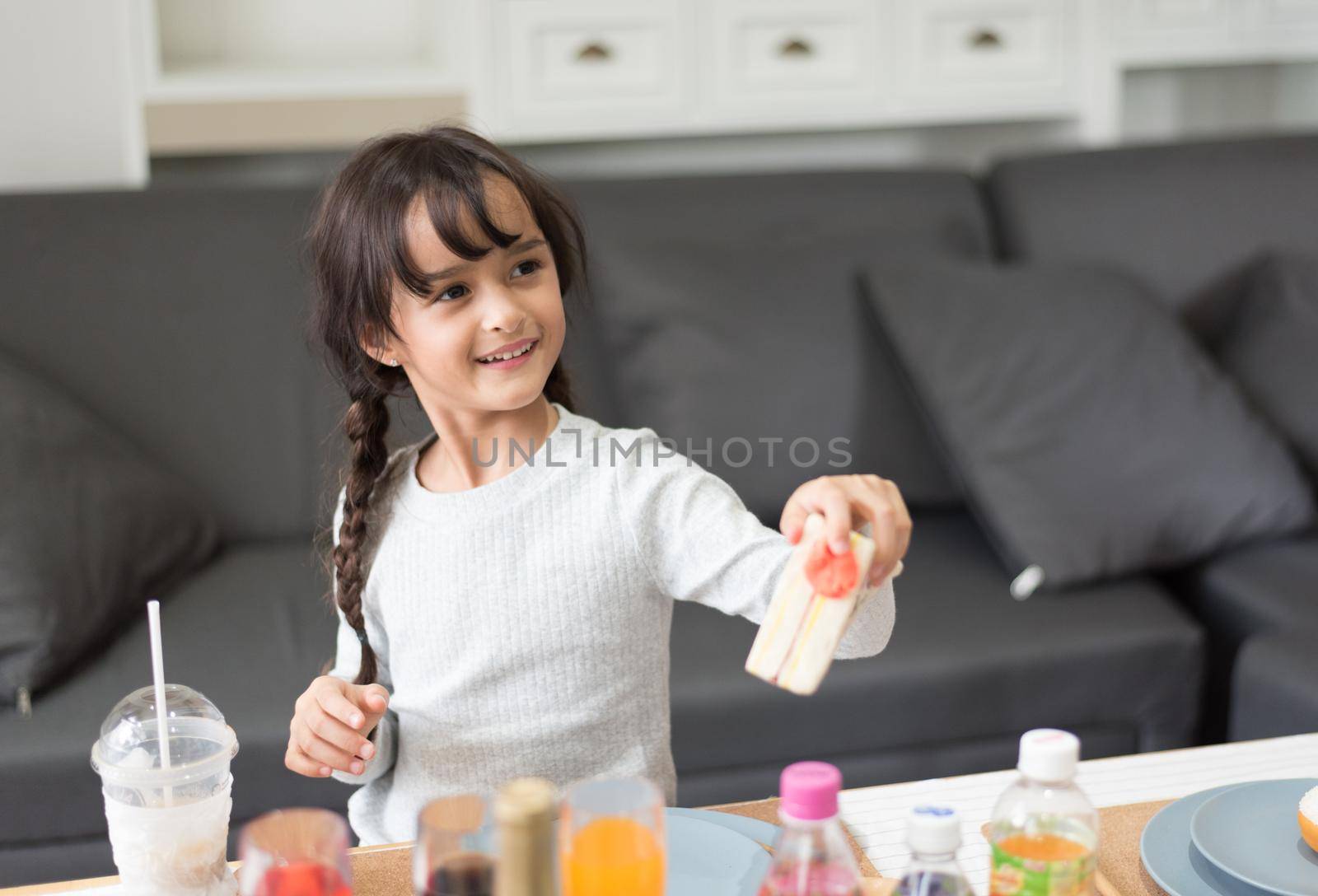 Happy little girl giving sandwich cooking toy as chef in living room. Playful of child and happiness education and development concept. Learning and leisure of cute girl. Nursery and daycare theme. by MiniStocker