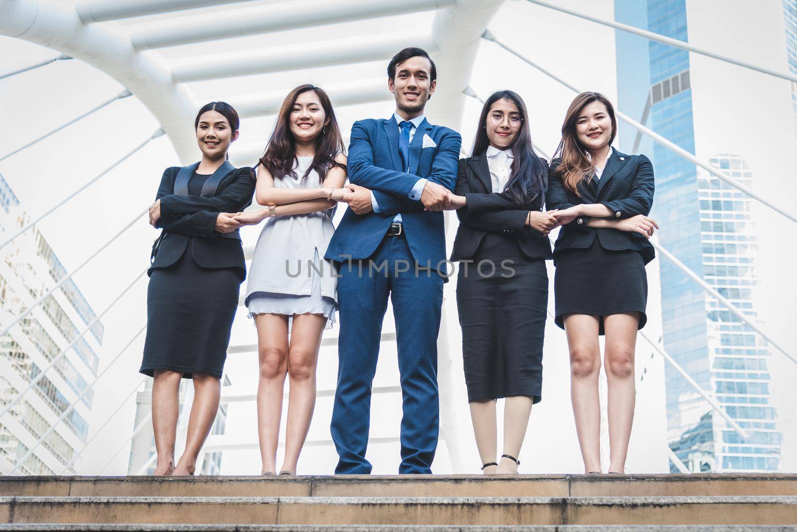Portrait of successful group of business people at outdoor urban. Happy businessmen and businesswomen standing as team in satisfaction gesture. Successful group of people smiling and looking at camera