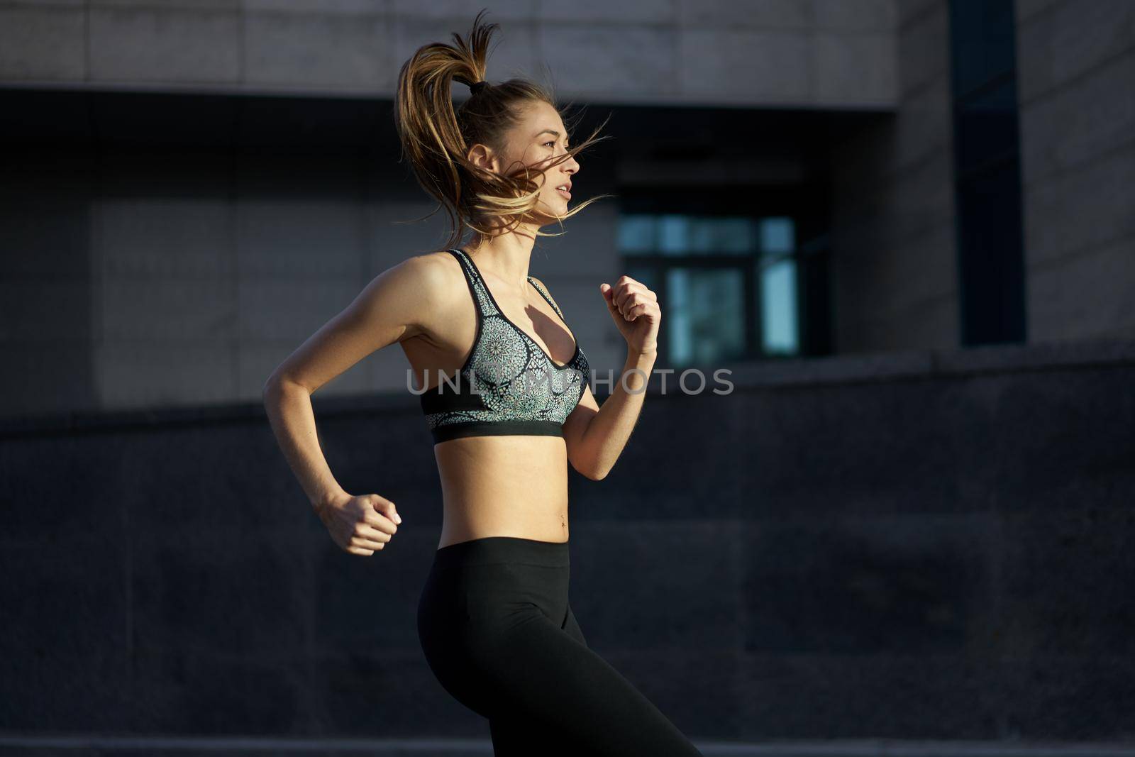 Woman running urban city street background Active sporty caucasian female morning workout Healthy lifestyle concept. Athletic person dressed sportswear do exercises Dark tone mood Corporate building