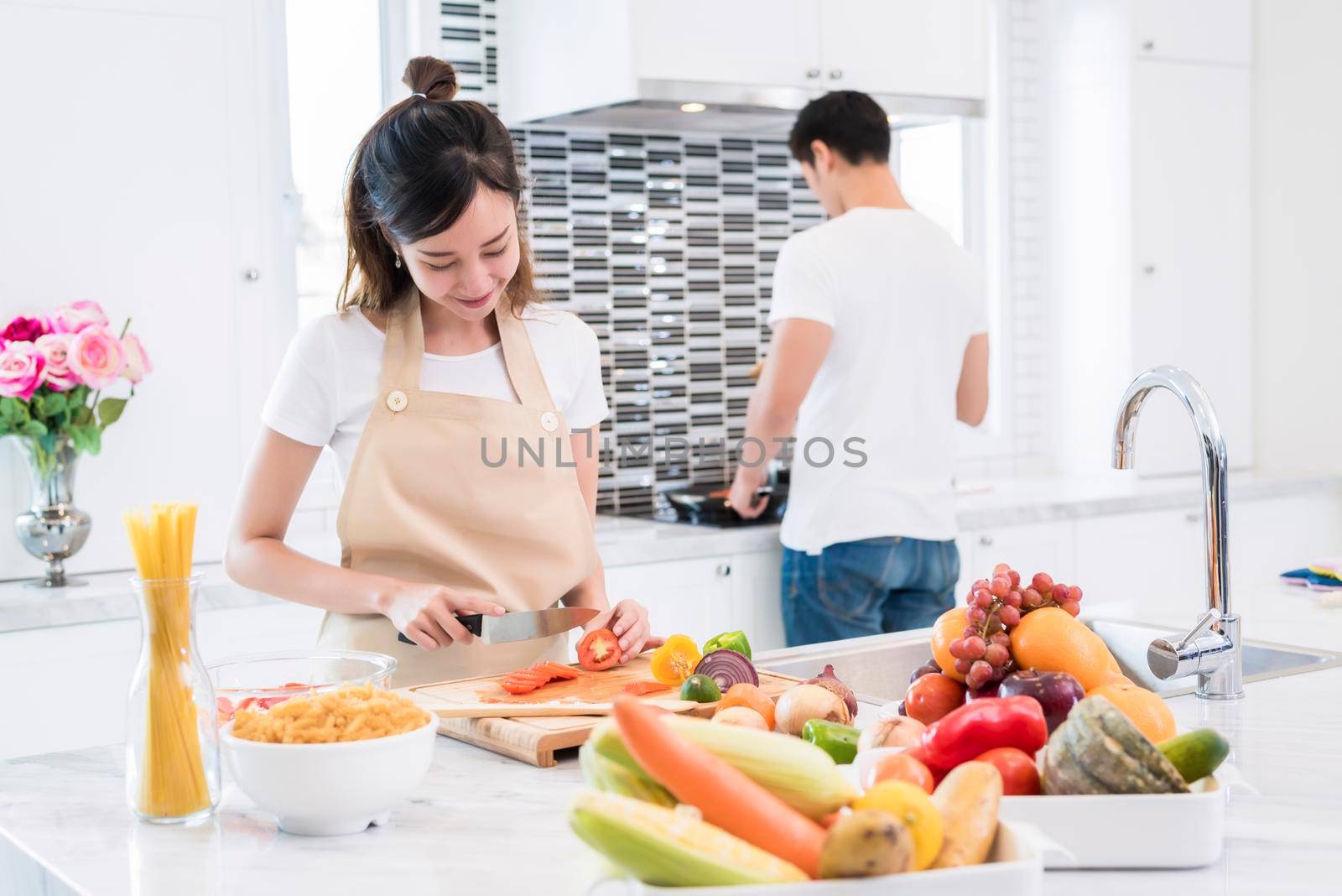 Asian lovers in kitchen. Woman slice vegetables and cooking, Man making spaghetti, Couple and Family concept. Honeymoon and Holidays theme by MiniStocker