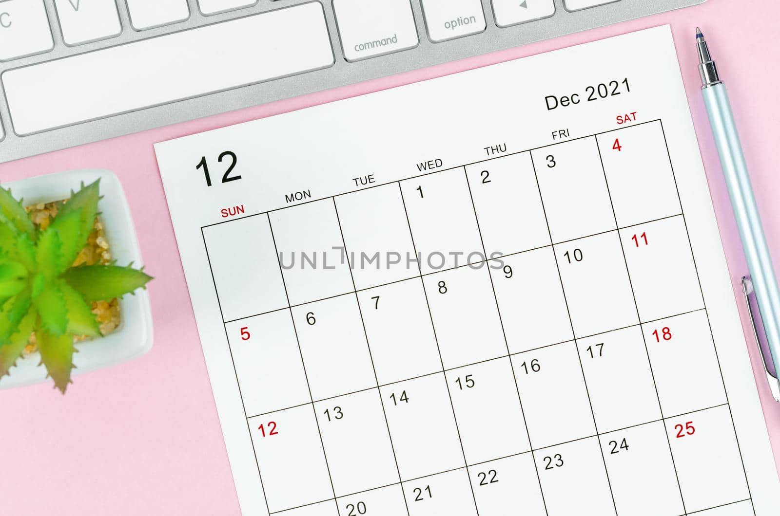 December 2021 calendar sheet with keyboard computer on pink background.
