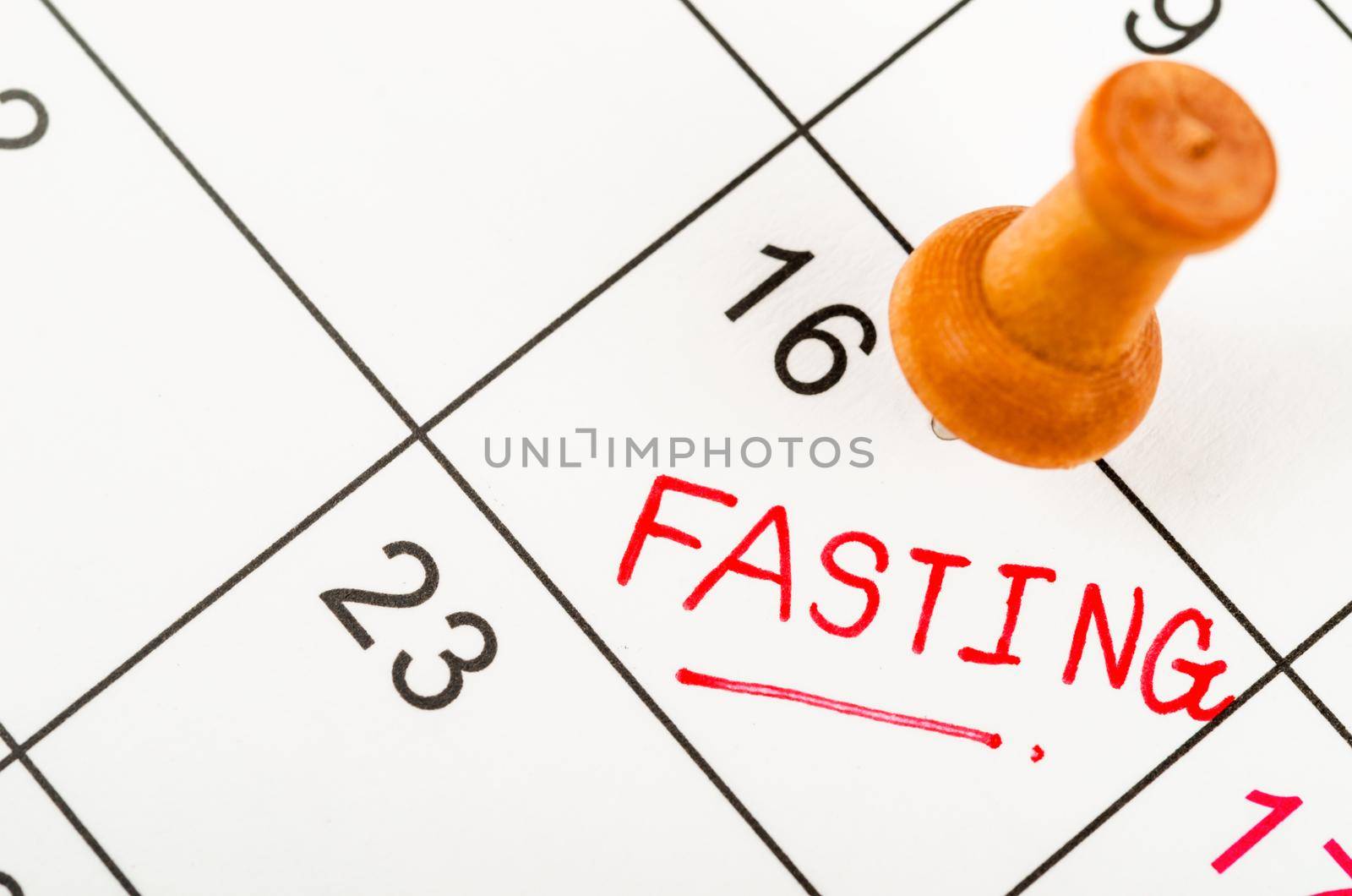 Fasting text writing in a calendar page with wooden pin. by Gamjai