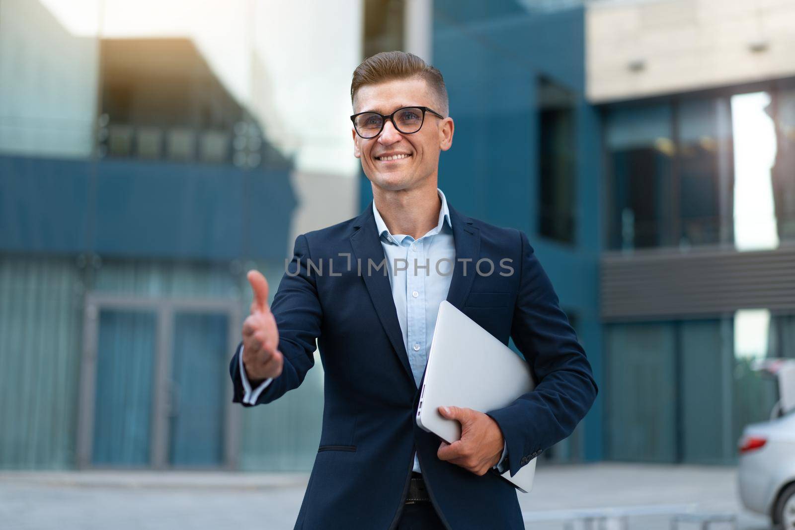 Business. Businessman Giving Hand For Handshake Welcome Gesture Adult Caucasian Male Business Person Holding Closed Laptop Give Hand Ready Handshake Office Building Background